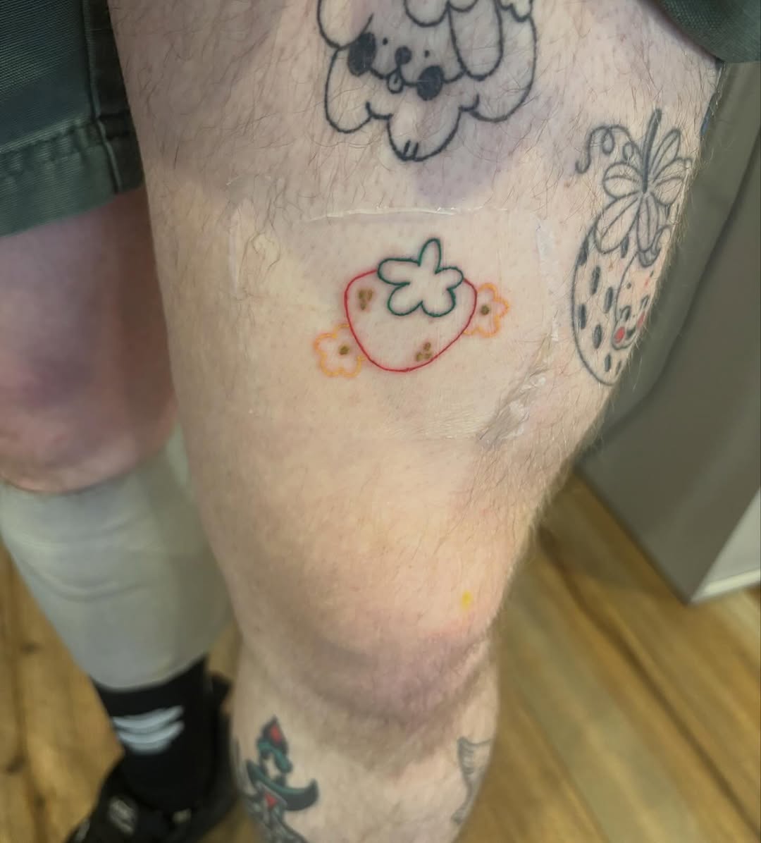 Strawberry with flowers ignorant tattoo on the leg by riley