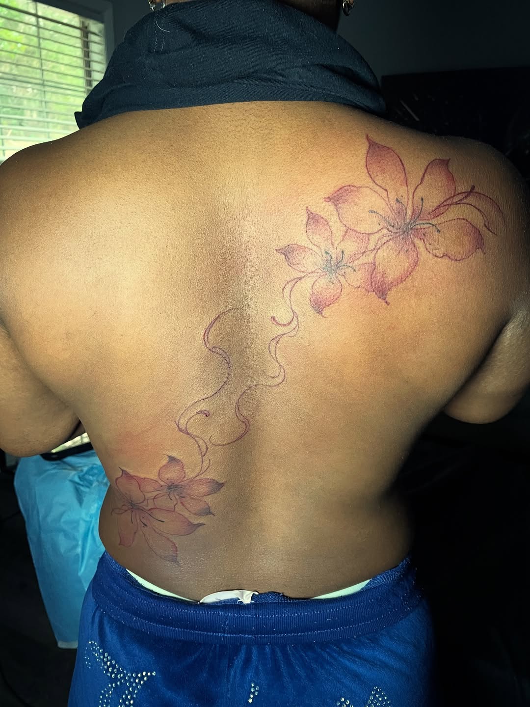 Two flowers with vine tattoo on the back by The Reelist Ink