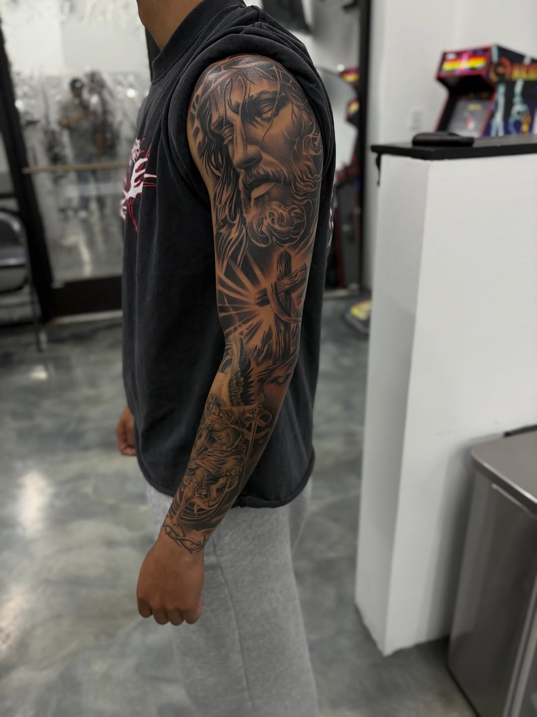 Jesus Christ and angel sleeve Chicano tattoo on the upper arm by Devin