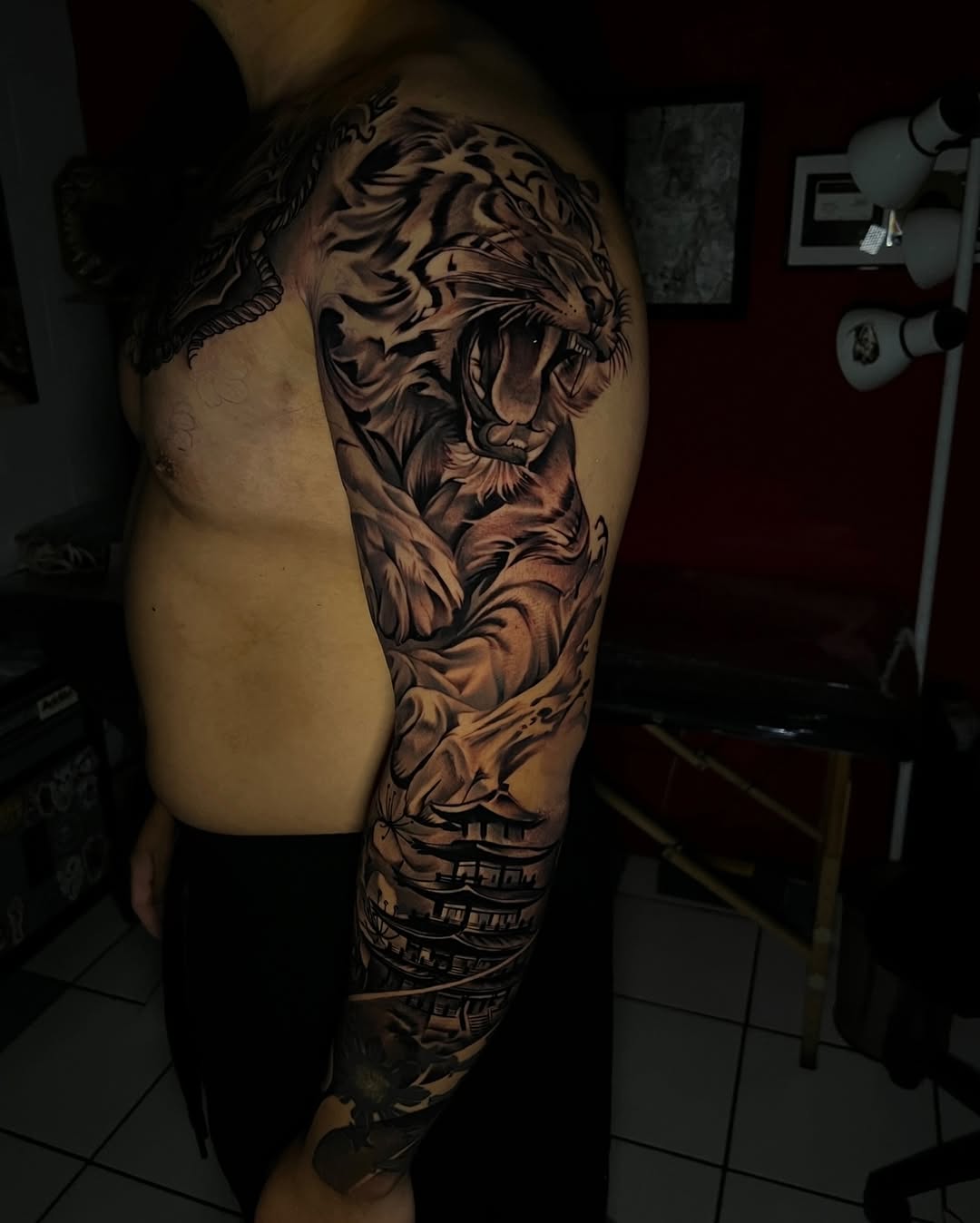 Tiger and pagoda Japanese tattoo on the upper arm by El Salvador Tattoo Artist