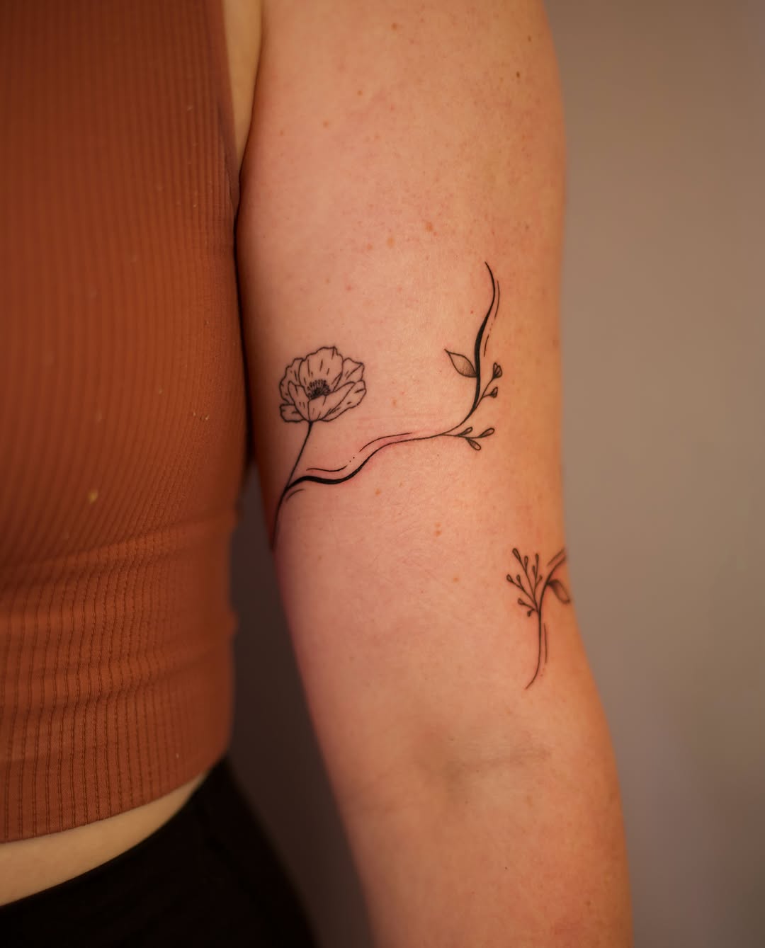 Flower and stem fine line tattoo on the forearm by Jess