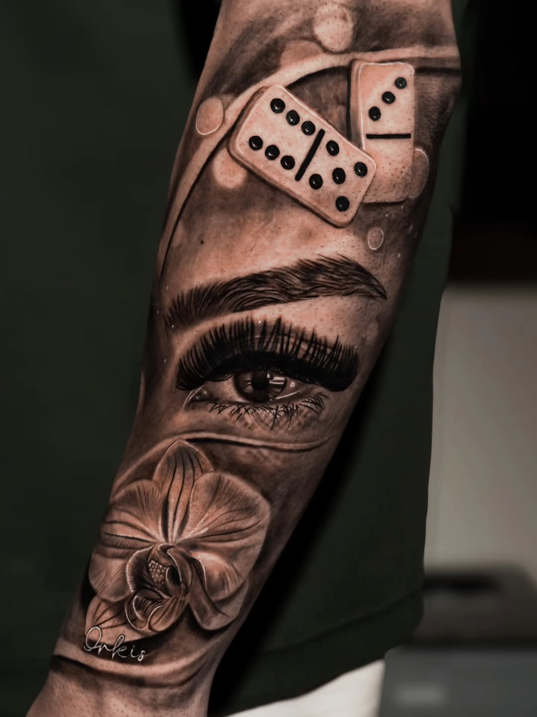 Eye, orchid, and dominoes realism tattoo on the forearm by Baxtertattoo