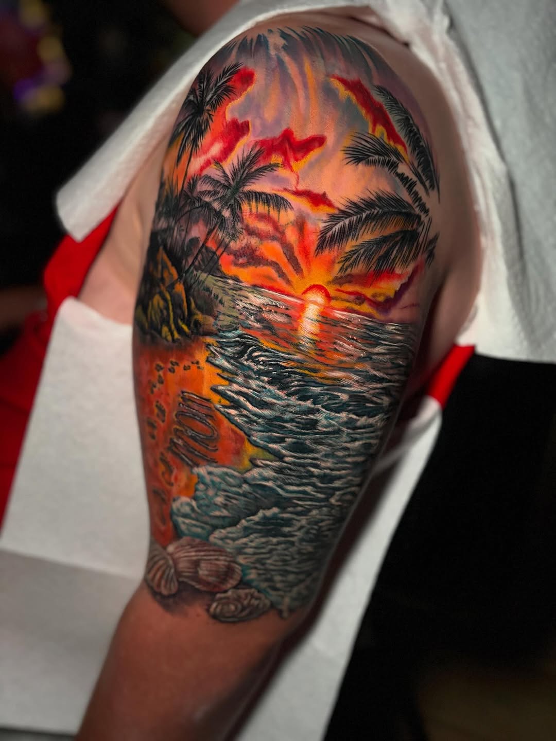 Tropical sunset beach scene realism tattoo on the forearm by Ashley Denise