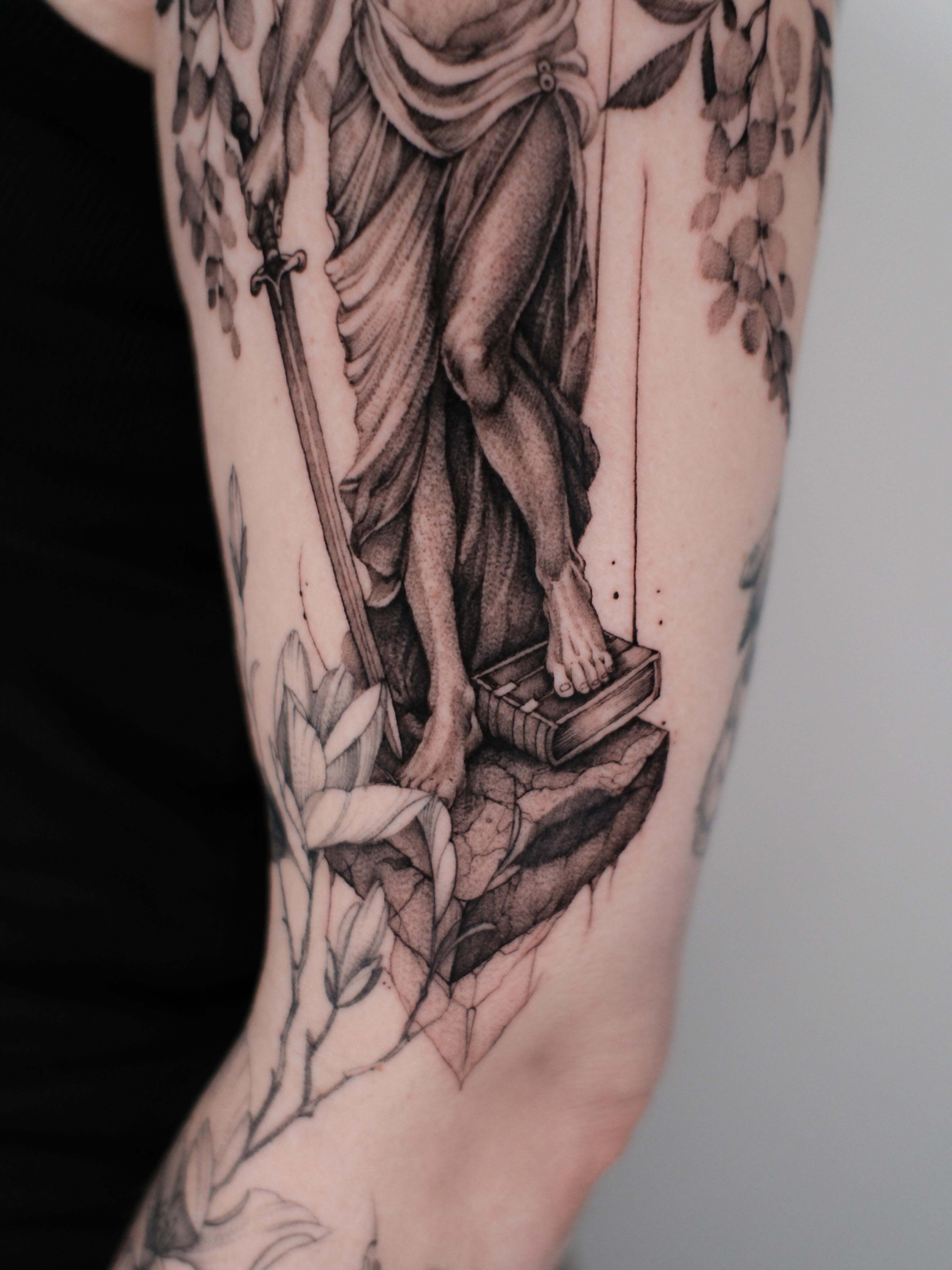Statue with sword and flowers sketch tattoo on the forearm by Anastasiia