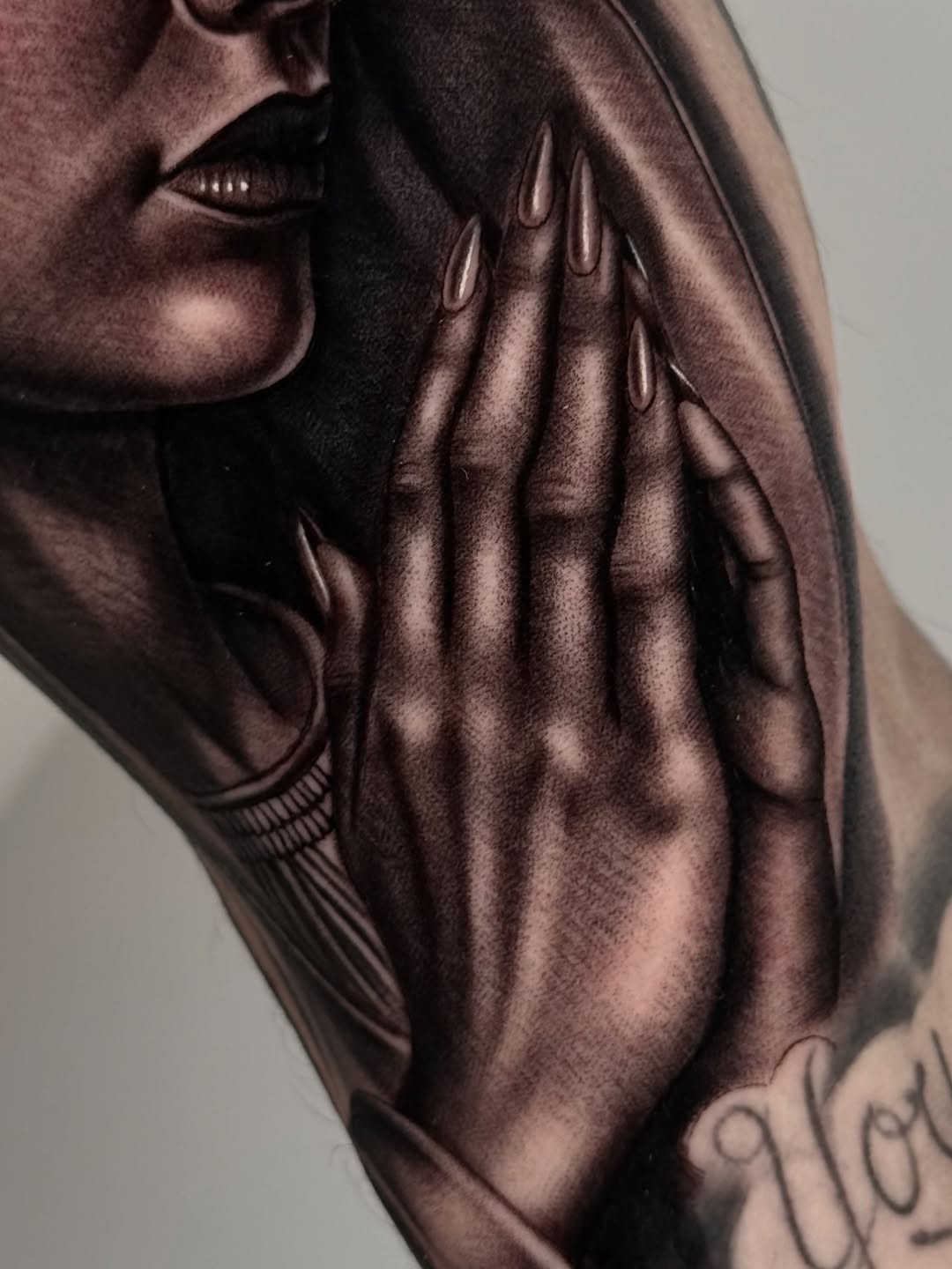 Woman's face and praying hands Chicano tattoo on the forearm by Fernando Andrade Jr