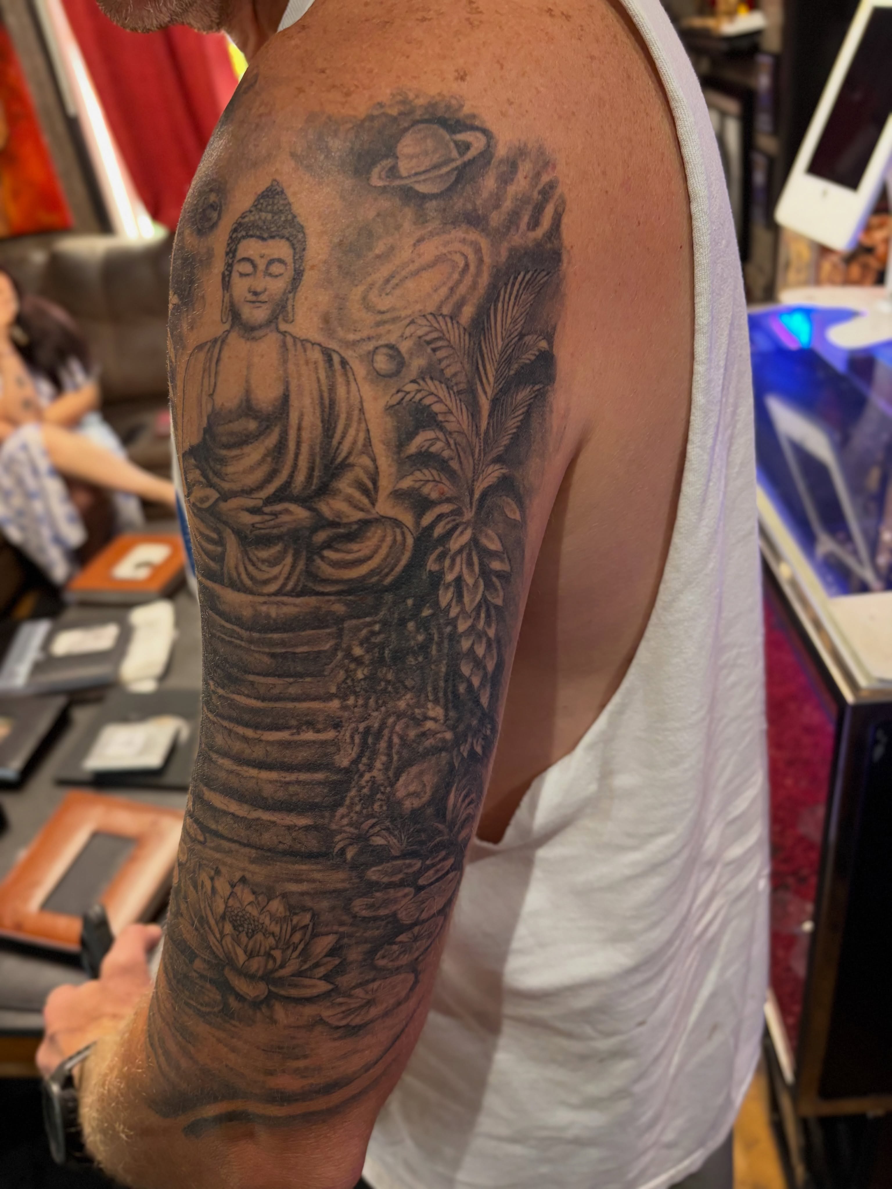 Buddha statue realism tattoo on the upper arm by Terik Whittaker