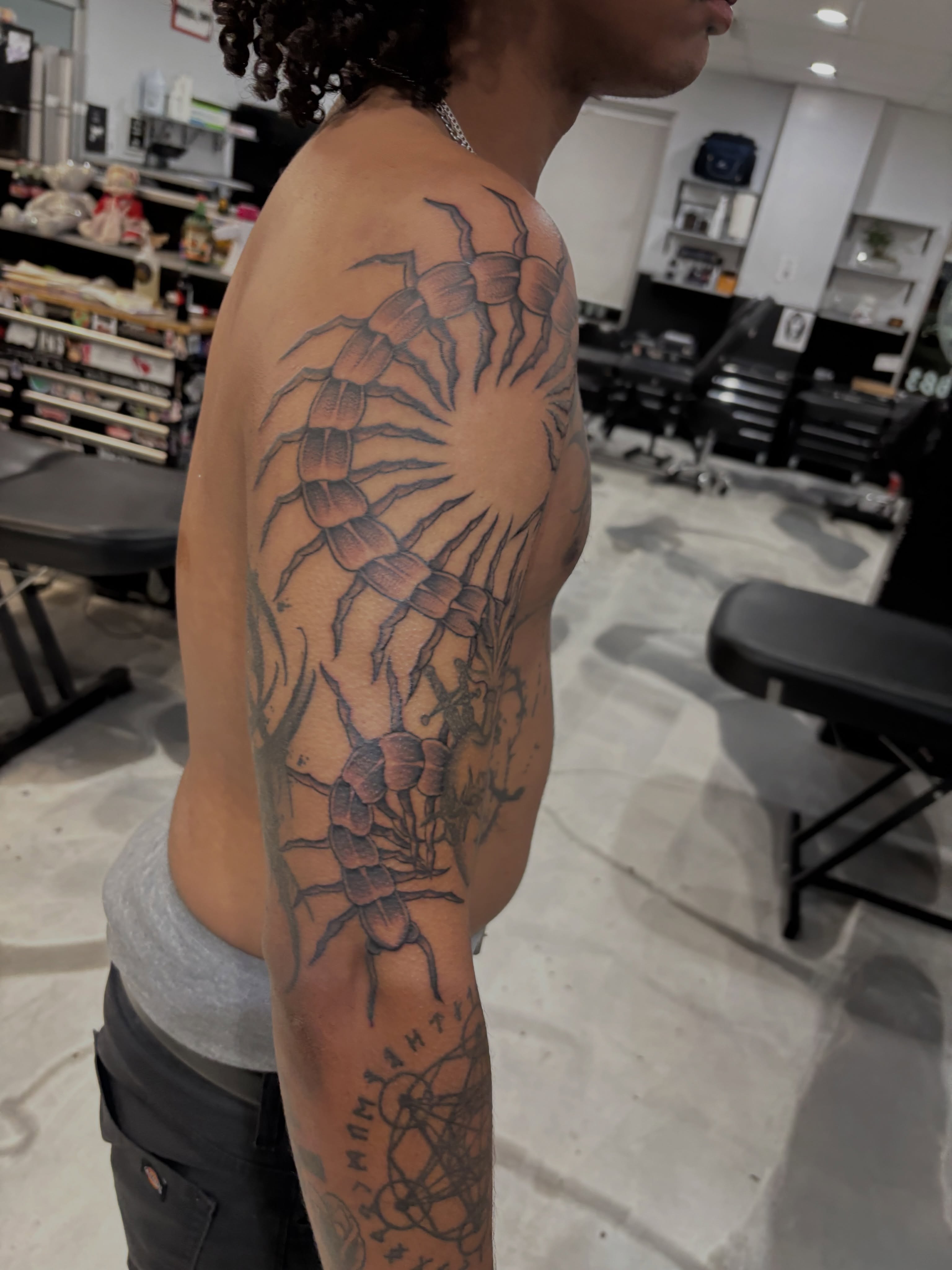 Centipede black and grey tattoo on the upper arm by Miklo Montoya