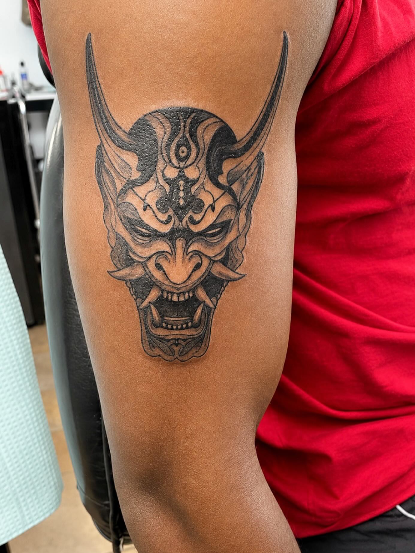 Demon mask black and grey tattoo on the forearm by Stoney