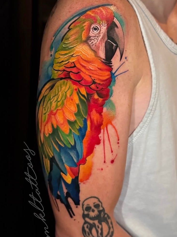 Macaw parrot watercolor tattoo on the upper arm by Mel K Lockett - Nashville Tattoo Artist