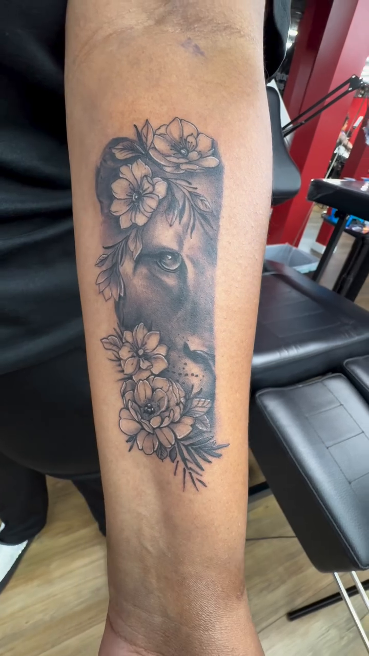 Lion head with flowers realism tattoo on the forearm by Art Plug