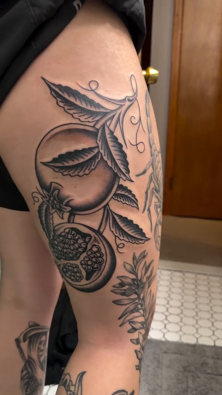 Pomegranate and leaves fine line tattoo on the thigh by 𝔍𝔲𝔩𝔦𝔞, New York, New York