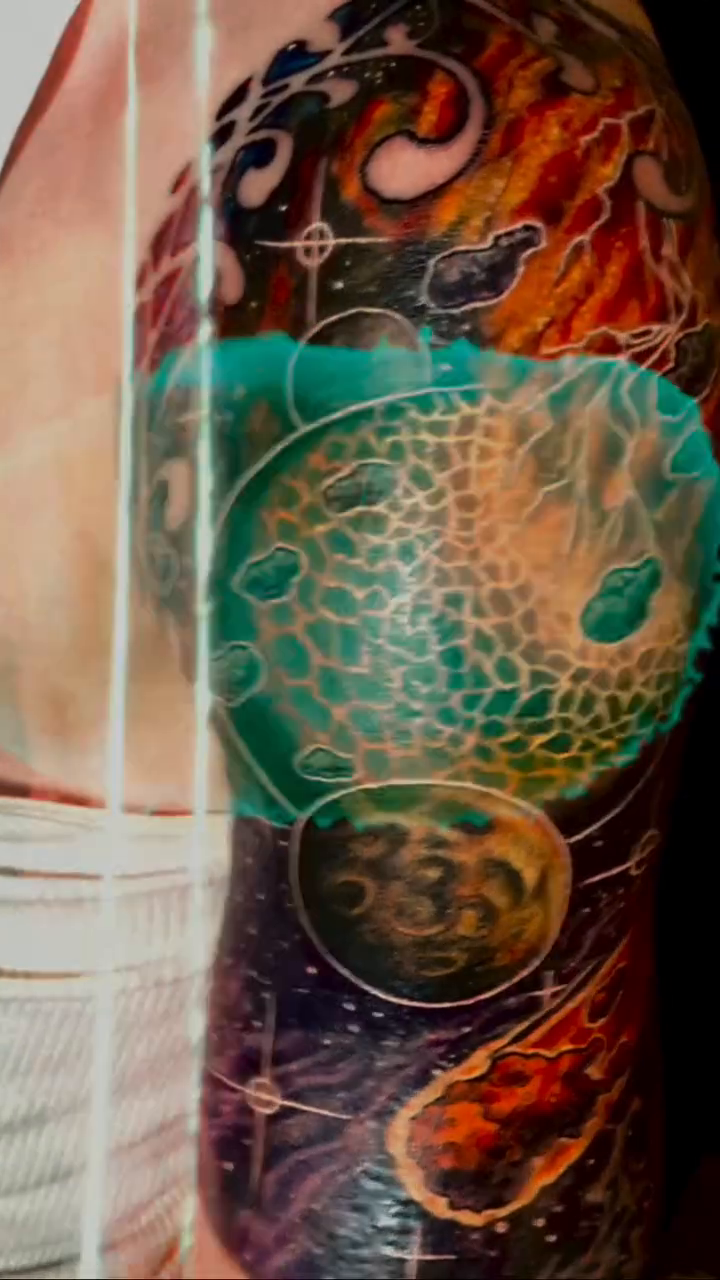 Cosmic sleeve with planets and nebulae watercolor tattoo on the upper arm by Patrick Delvar