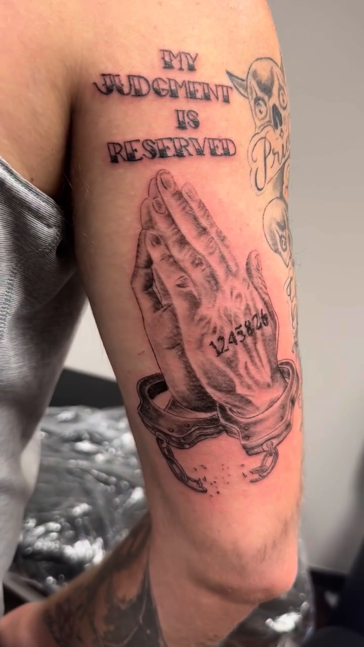 Praying hands with text Chicano tattoo on the upper arm by Willi Tattoos👹