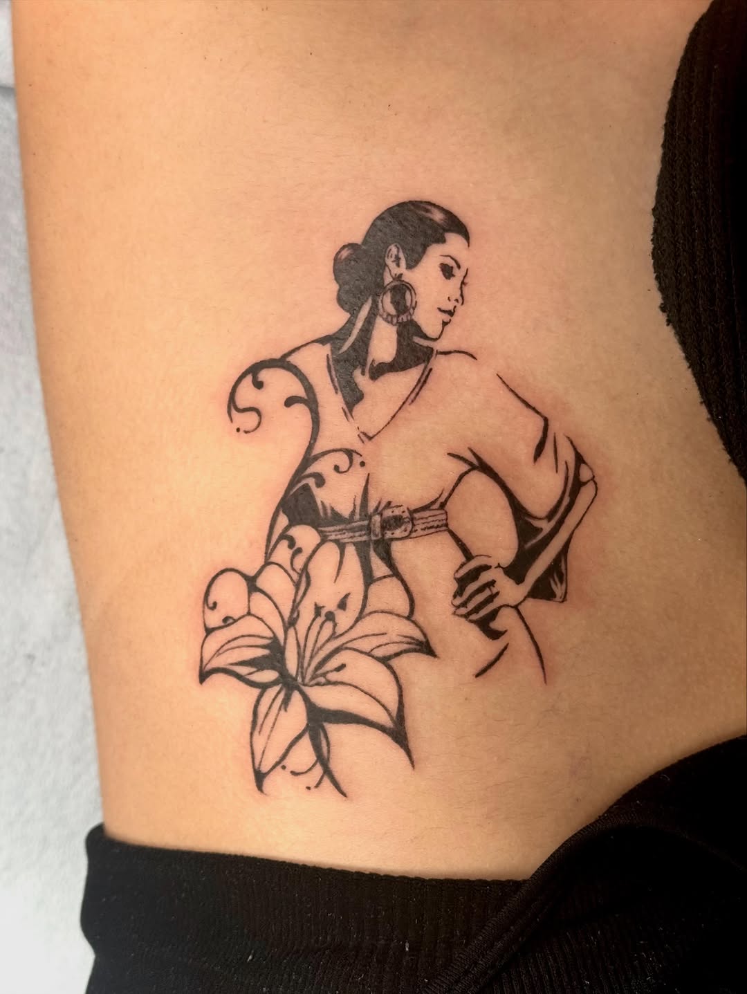 Woman with lily fine line tattoo by Taylor Alicia