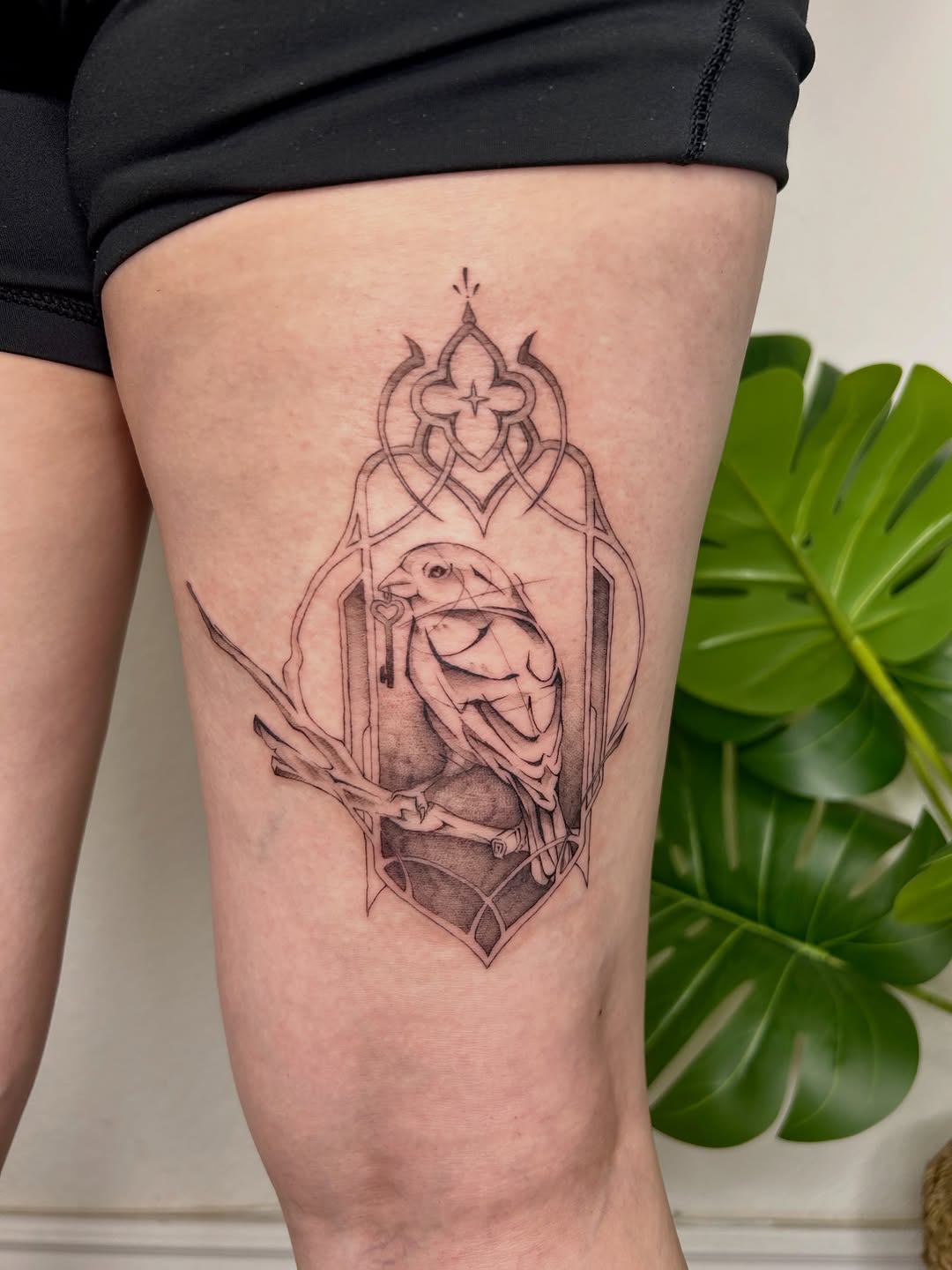 Bird in ornate frame fine line tattoo on the thigh by Miri