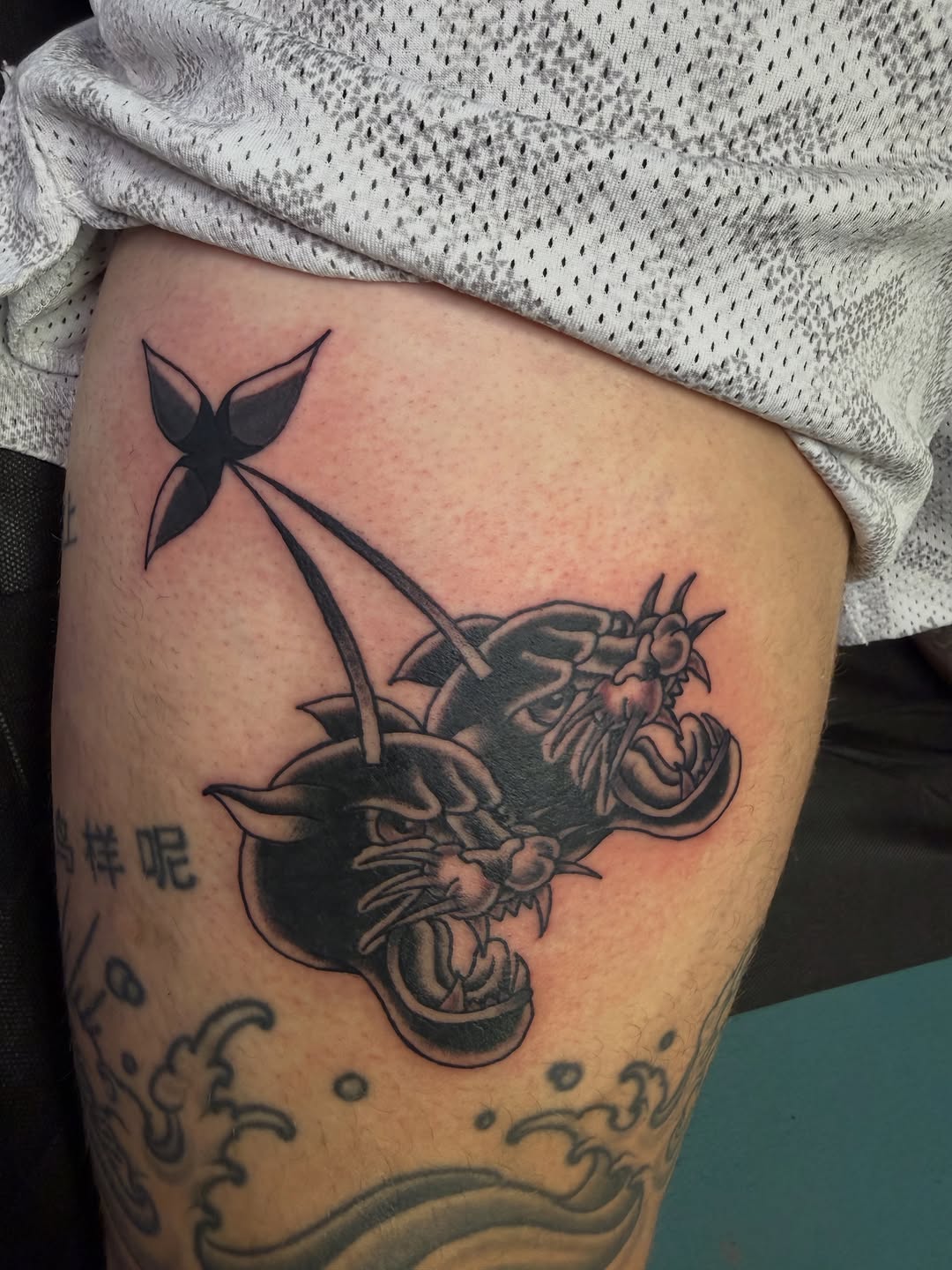 Two panthers and a shuriken realism tattoo on the thigh by Nick Tumminello