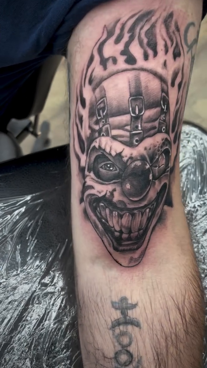 Scary clown with flames realism tattoo on the forearm by Robbie Reel, Wichita, Kansas
