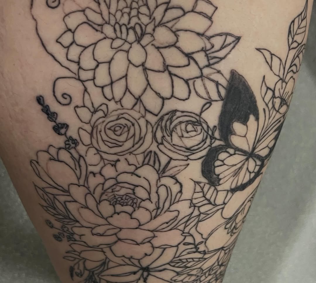 Floral arrangement with butterfly fine line tattoo on the thigh by The feminine ink