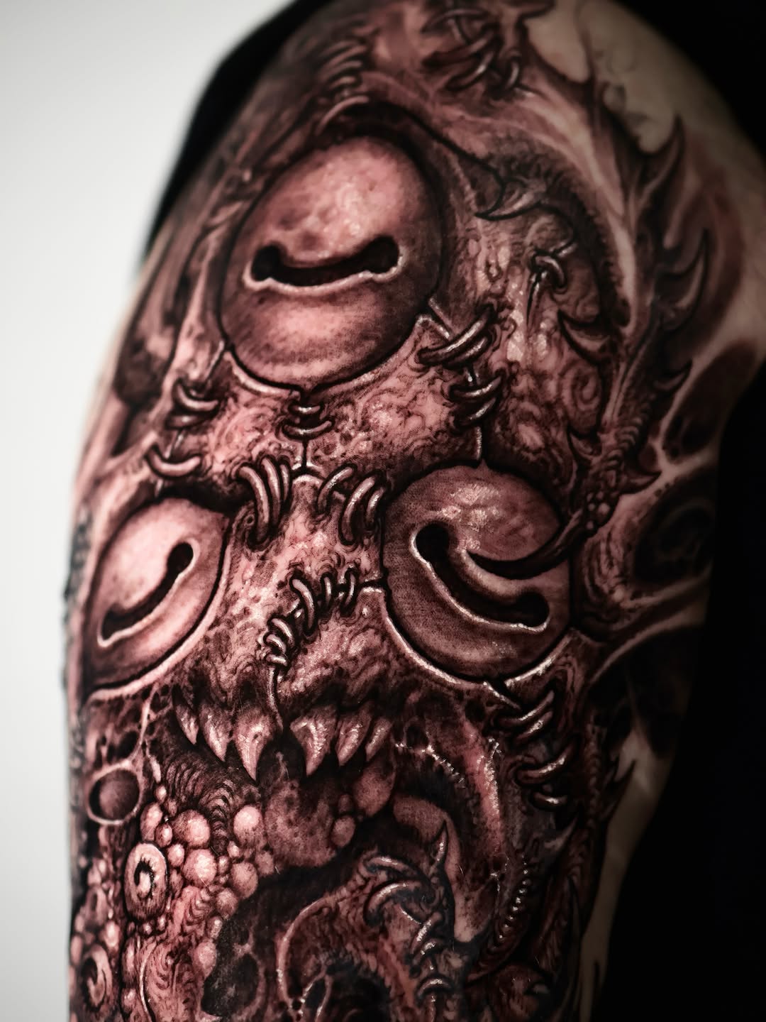 Biomechanical creature face dark art tattoo on the upper arm by Dark tattoo