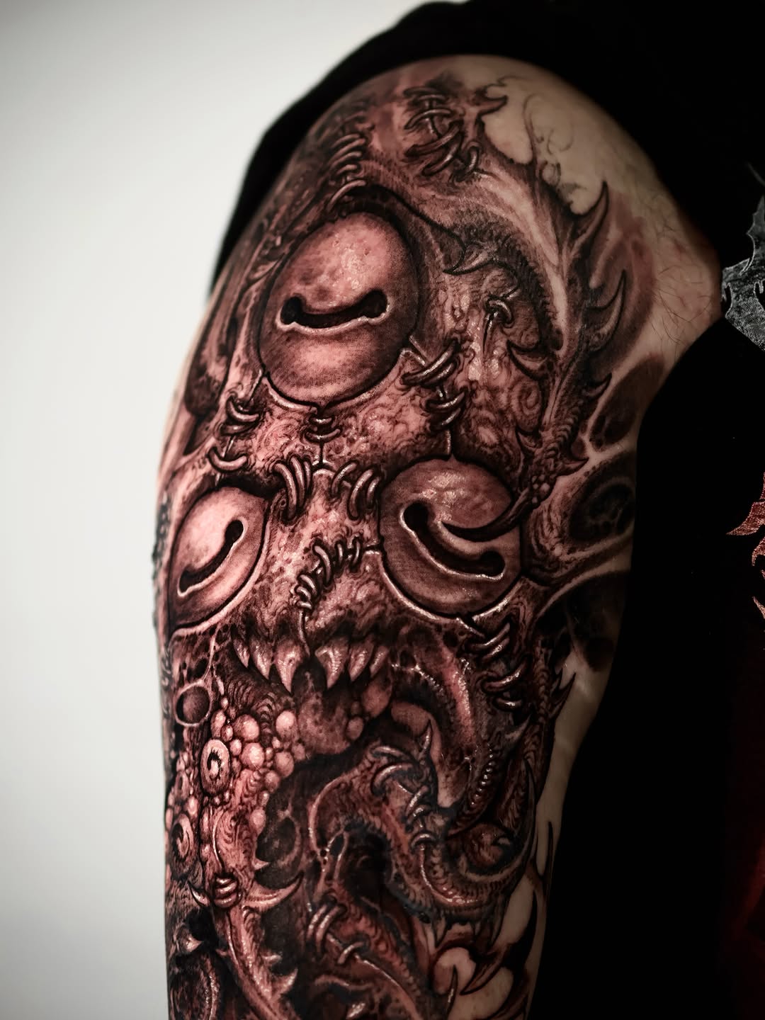 Demonic creature face dark art tattoo on the upper arm by Dark tattoo