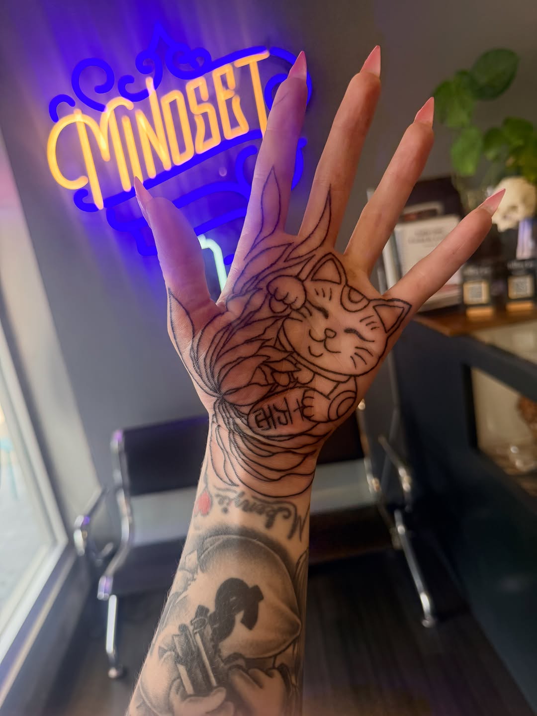 Cat face with floral elements tattoo on the hand by Maggie George