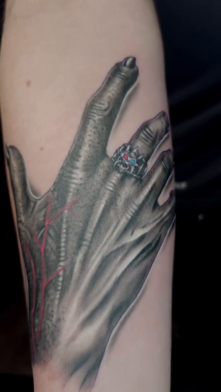 A skeletal hand with a ring realism tattoo on the forearm by Ian Duncanson