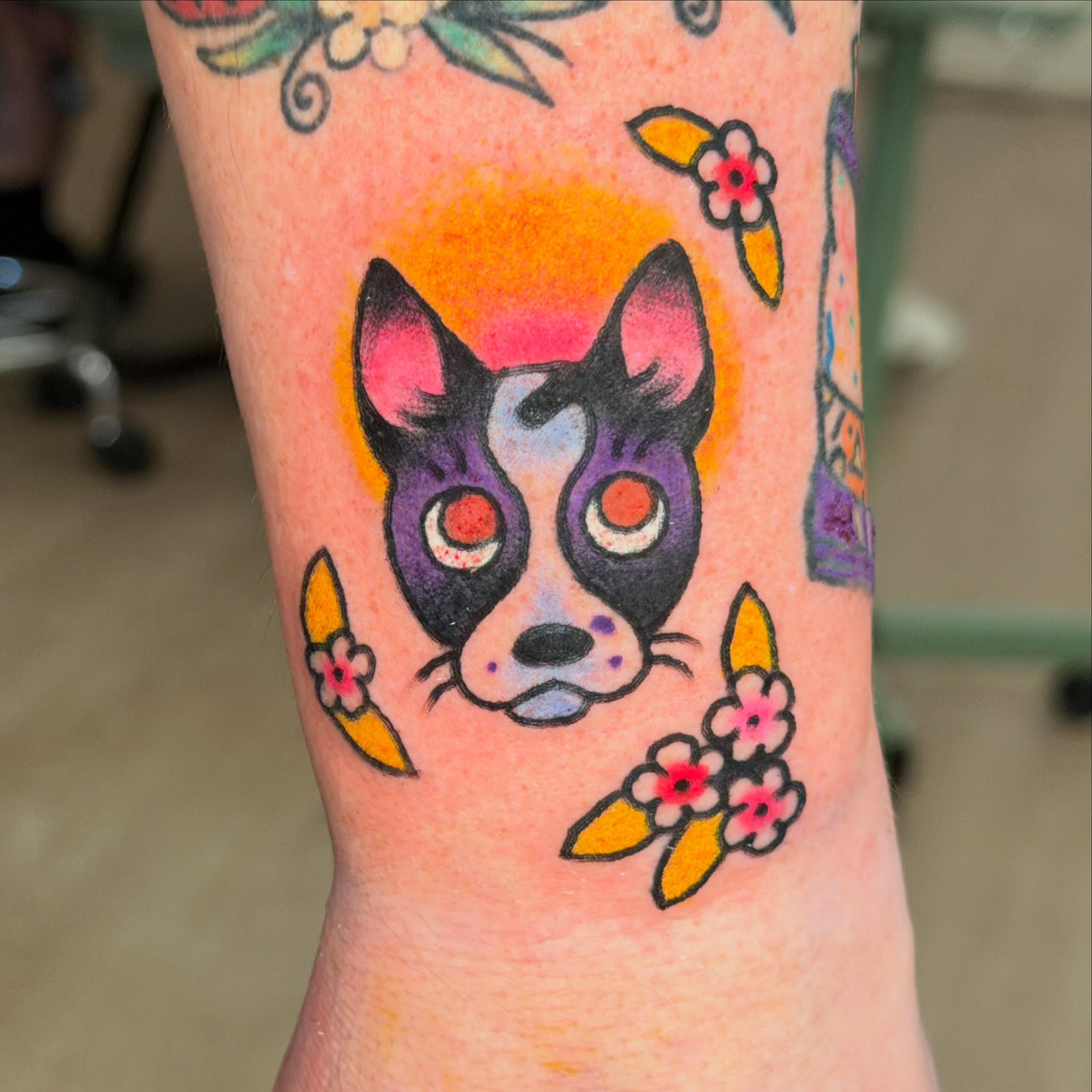Dog with flowers American traditional tattoo on the forearm by Gus Roach Graves