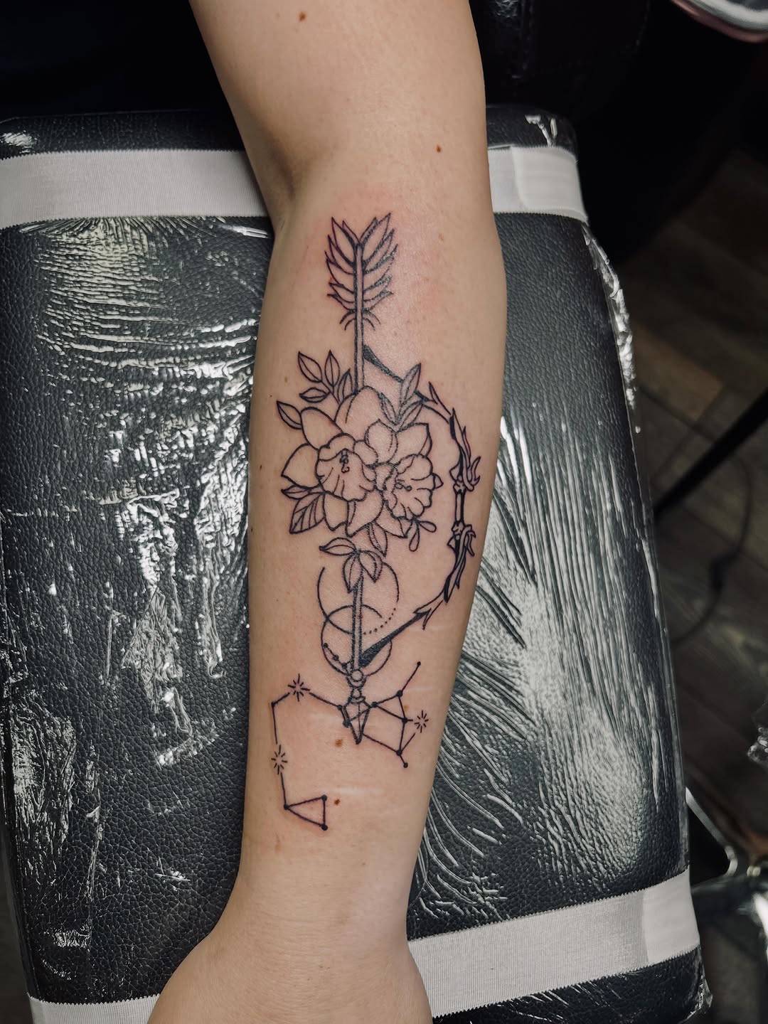 Arrow with flowers and constellation ornamental tattoo on the forearm by Bjorn Bjornstad, Dubuque, Iowa