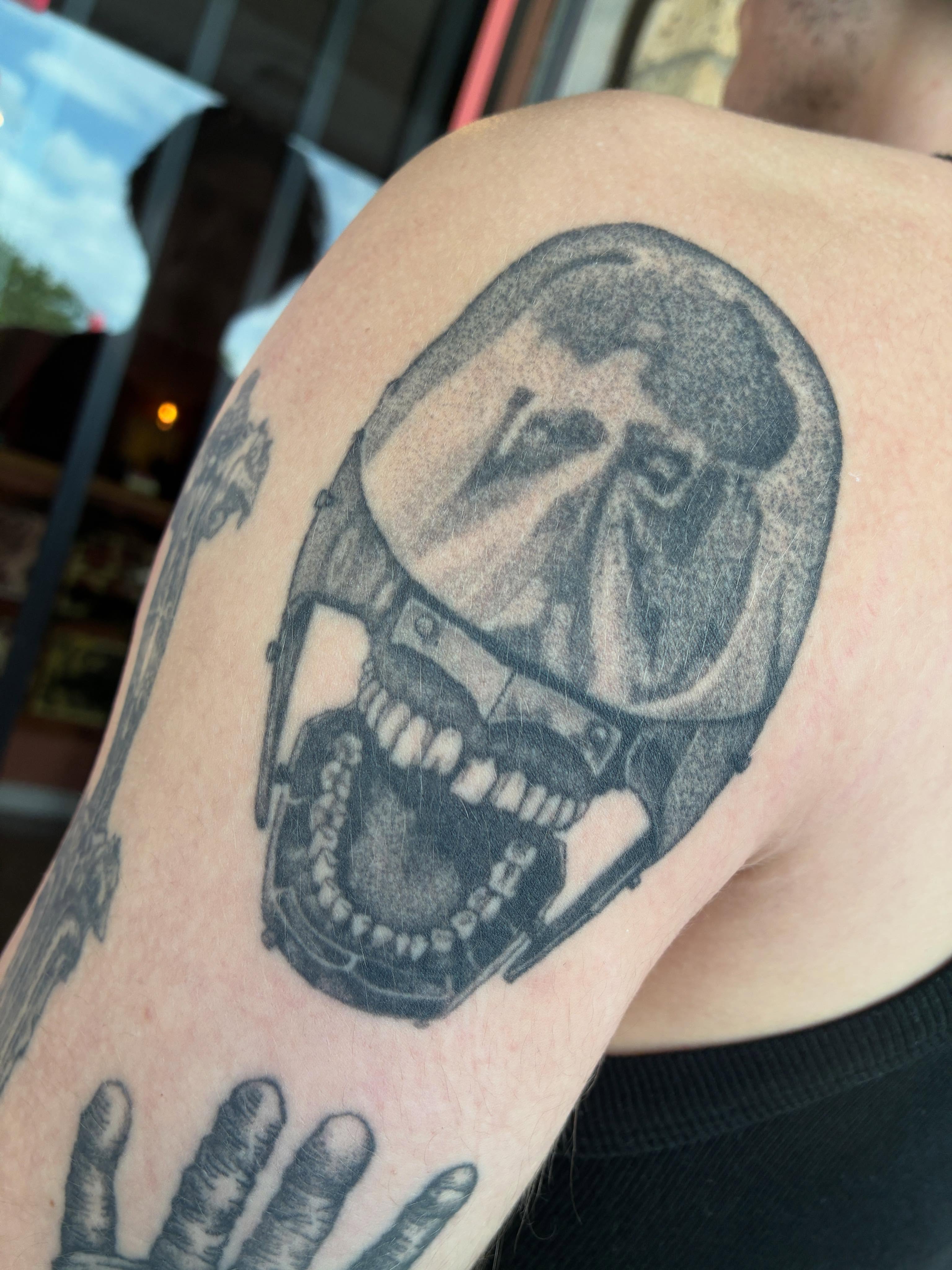 Helmeted skull black and grey tattoo on the upper arm by Zachary R Bobkoff