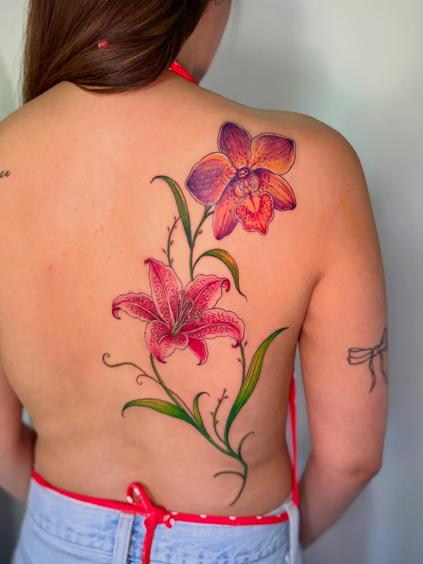 Lily and orchid realism tattoo on the back by Cat girl tattoo