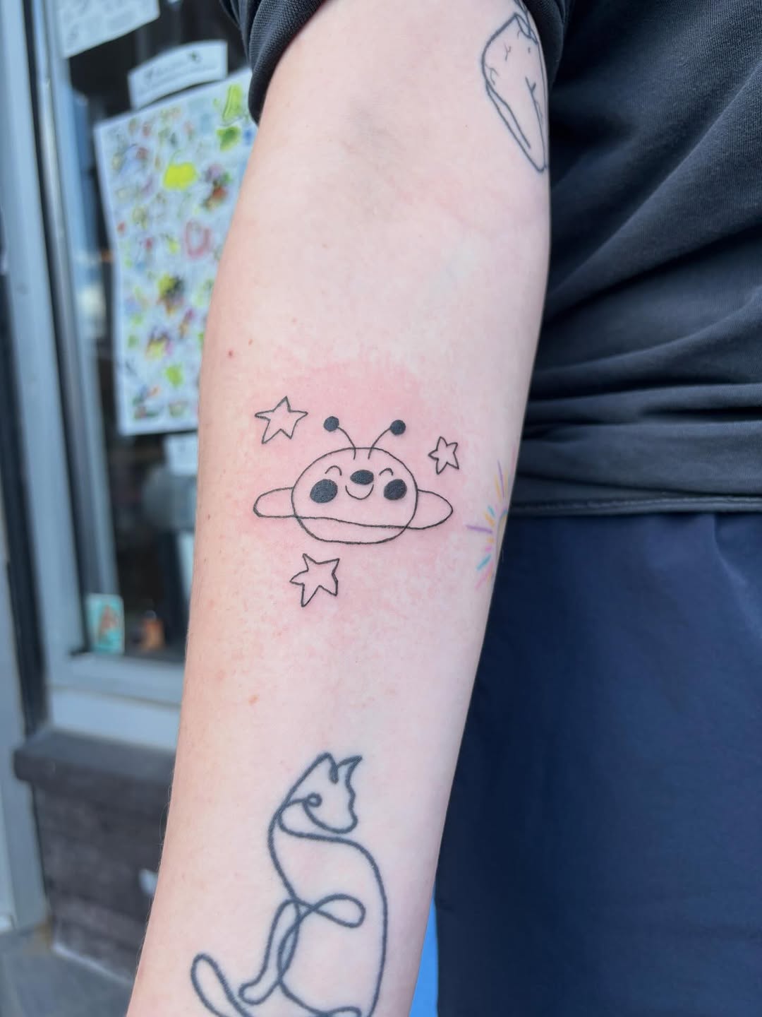 Cartoon planet with stars new school tattoo on the forearm by riley