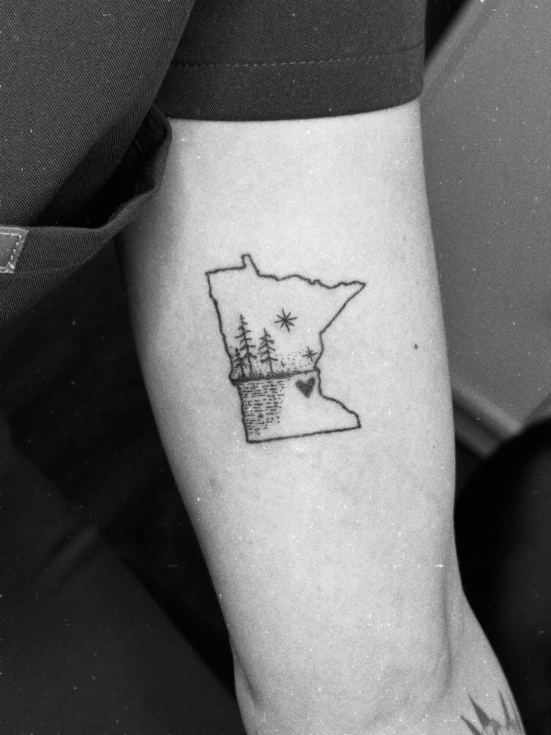 Minnesota outline with trees and heart minimalist tattoo on the forearm by Liz