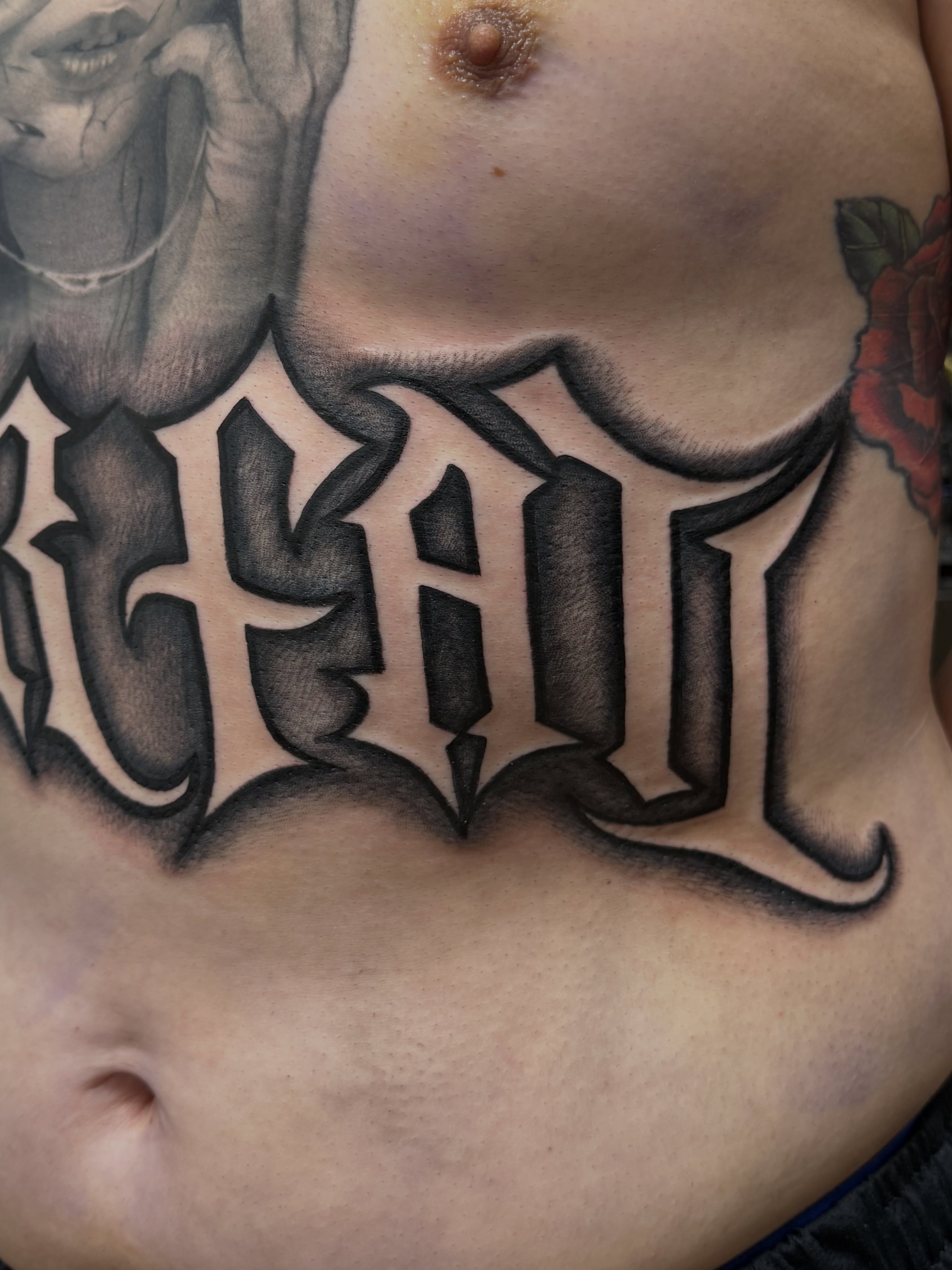 Lettering black and grey tattoo on the chest by Royal Martinez