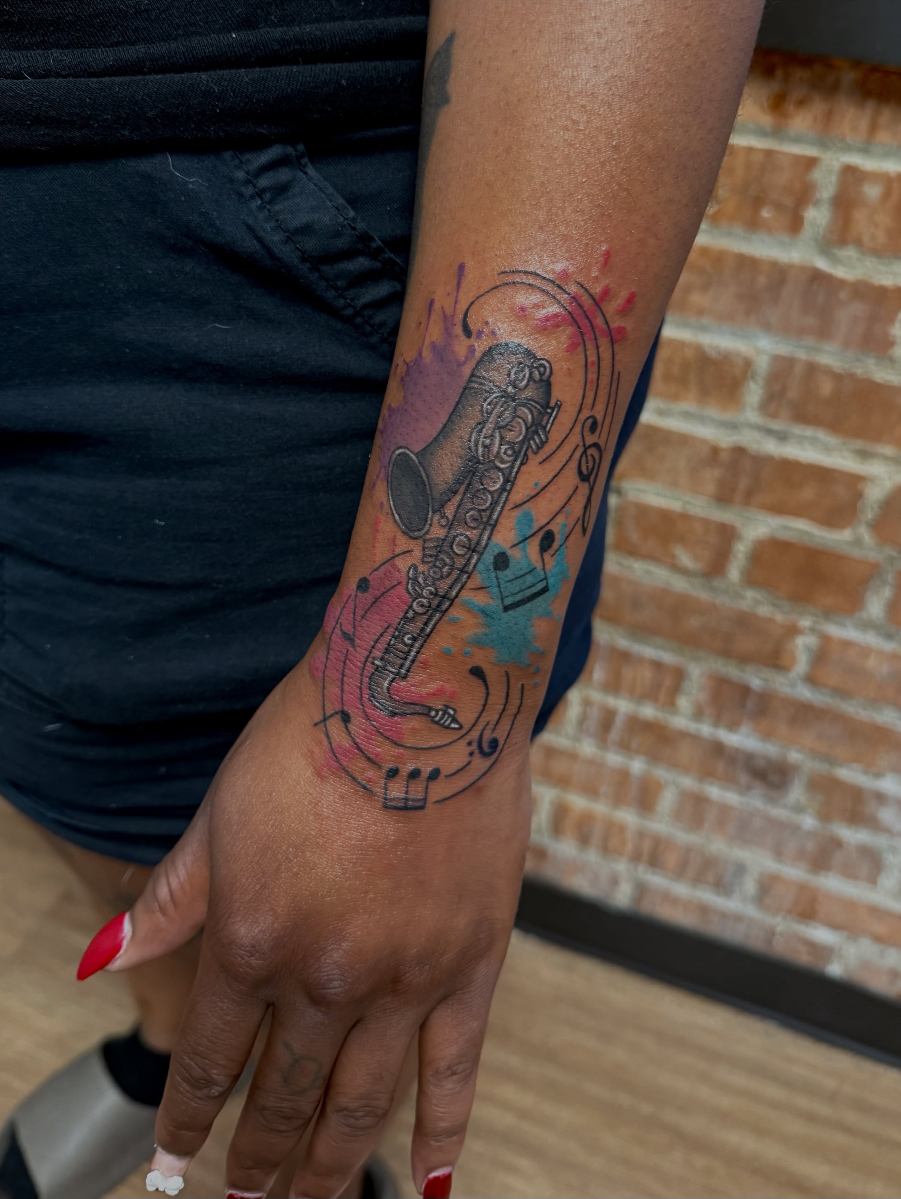 Tuba and musical notes new school tattoo on the forearm by Royal Martinez