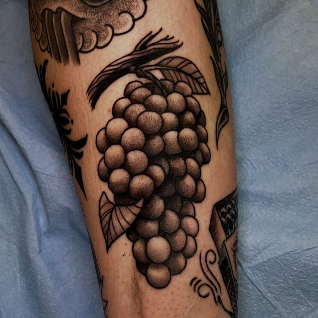 Grapes black and grey tattoo on the forearm by Evan Perrine