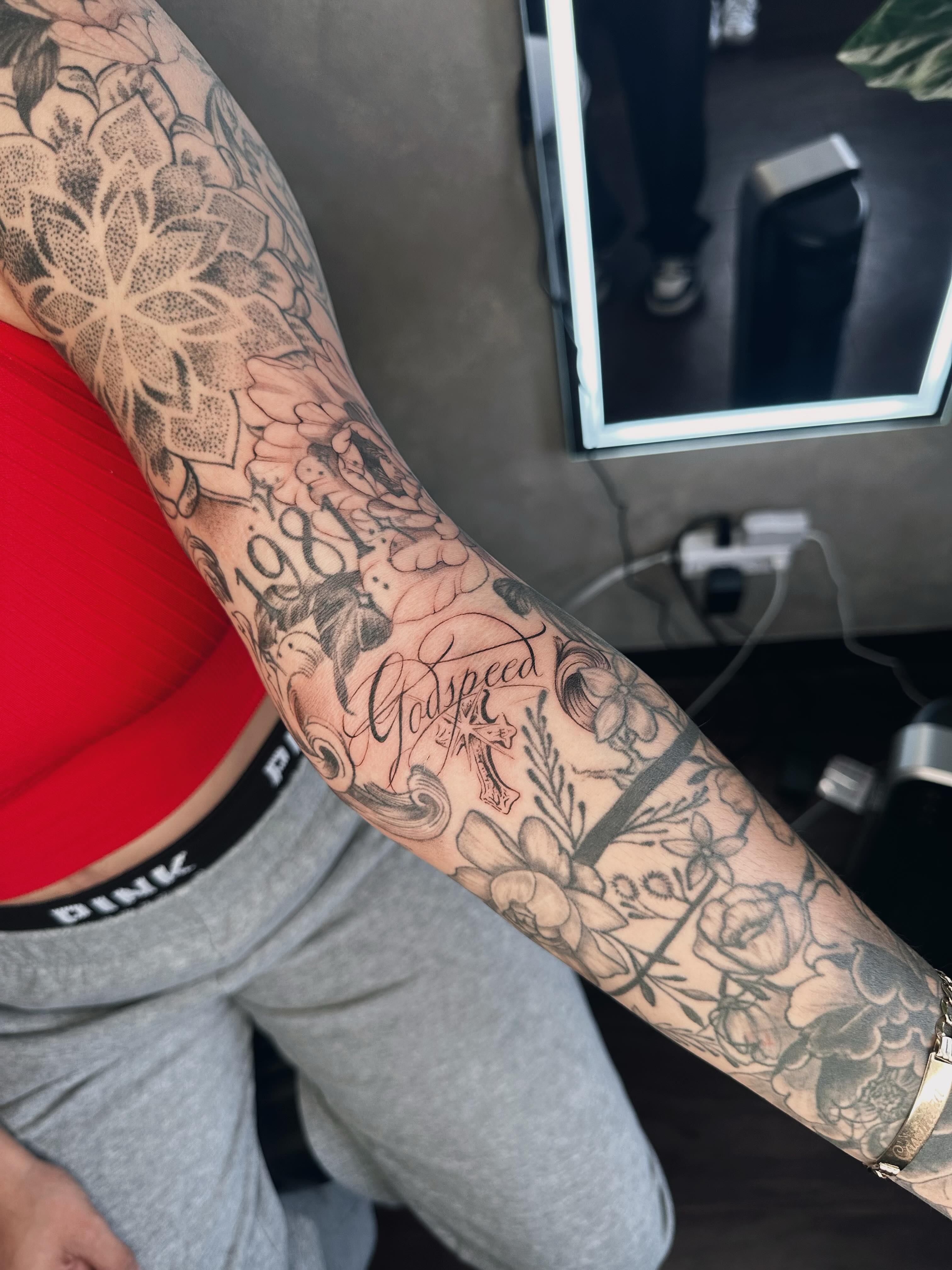 Floral and script dotwork tattoo on the forearm by Liv