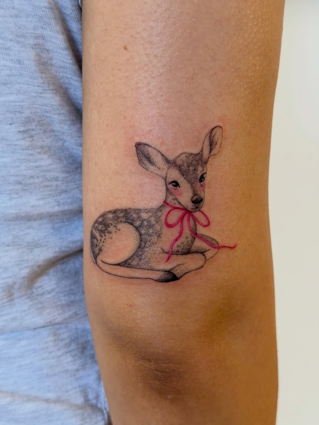 Fawn with pink ribbon fine line tattoo on the forearm by Sienna (jj) Hicks