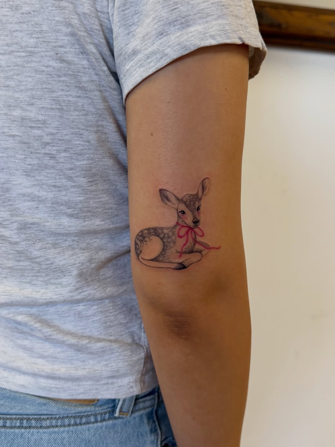 Fawn with pink bow fine line tattoo on the forearm by Sienna (jj) Hicks