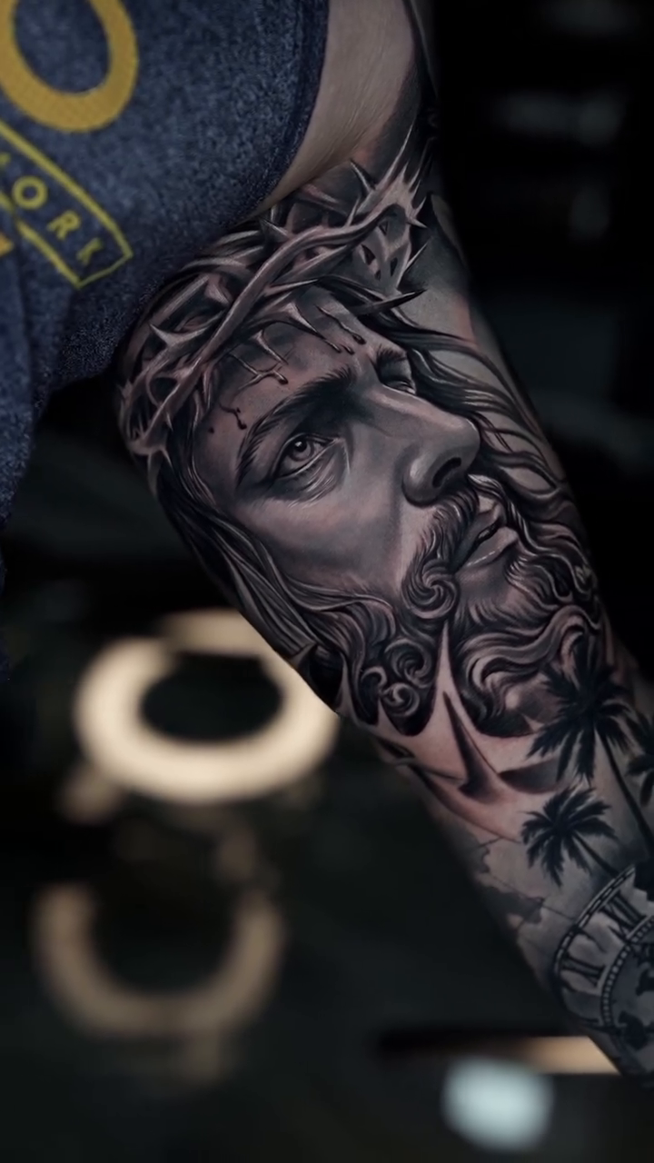 Jesus Christ portrait with palm trees Chicano tattoo on the forearm by Andres García Baeza