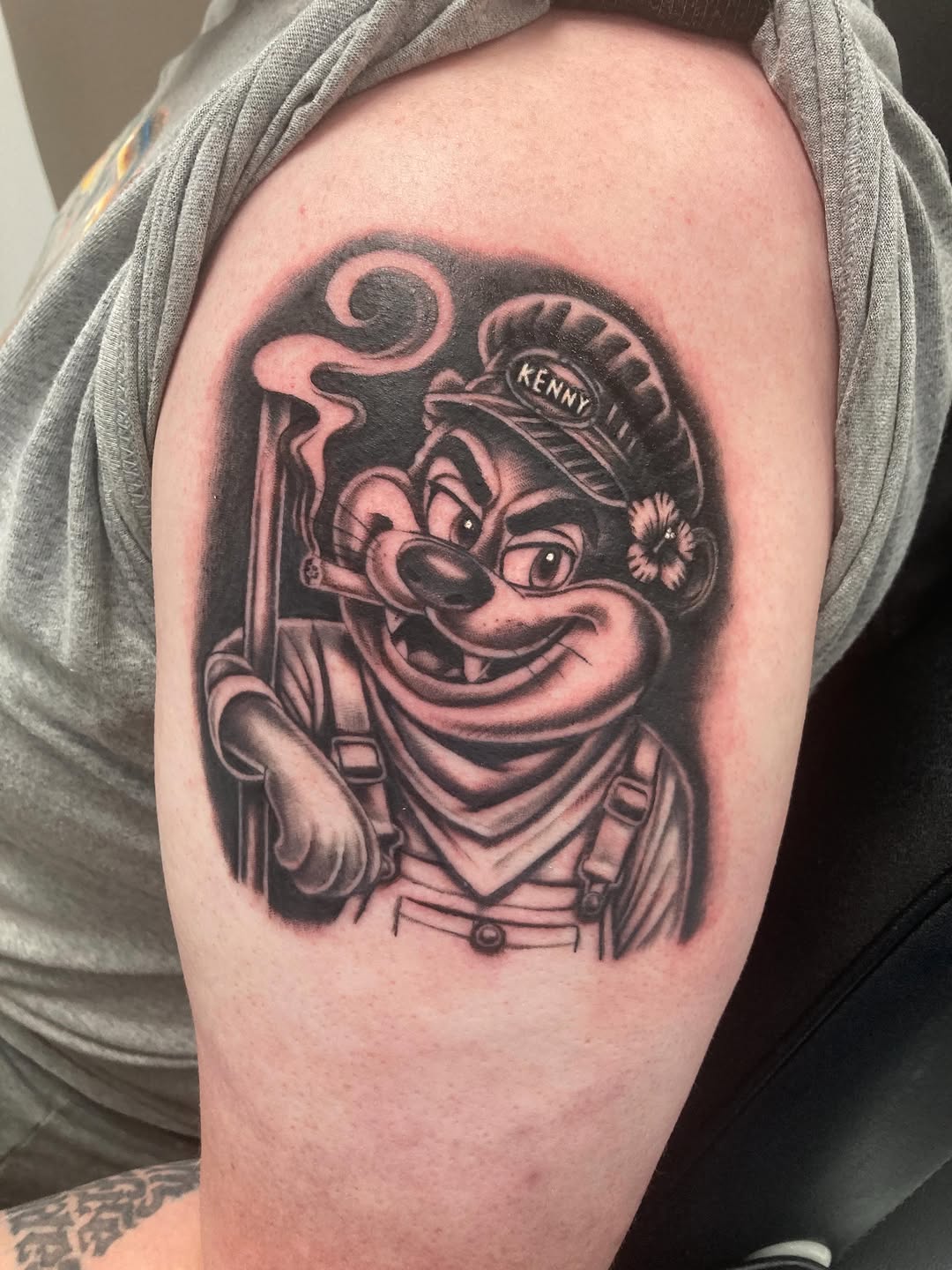 Cartoon character with hat and cigar tattoo on the shoulder by Timothy Murtaugh