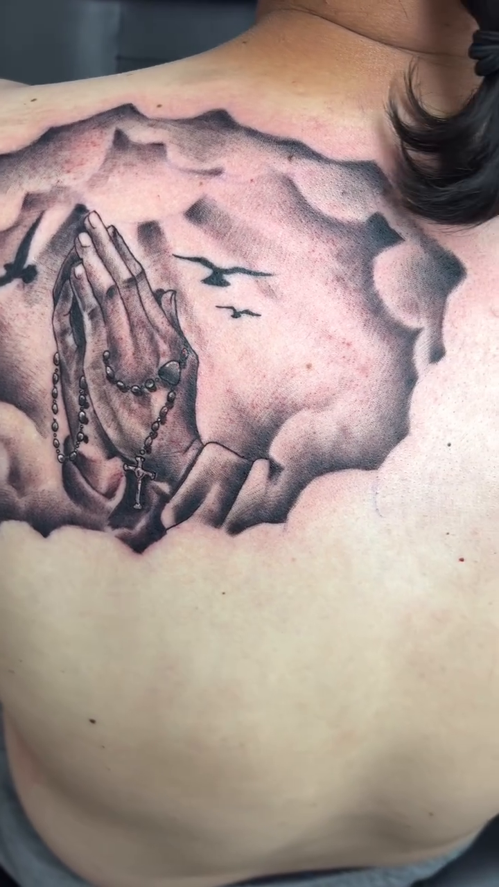 Praying hands with rosary and birds Chicano tattoo on the back by Art Plug