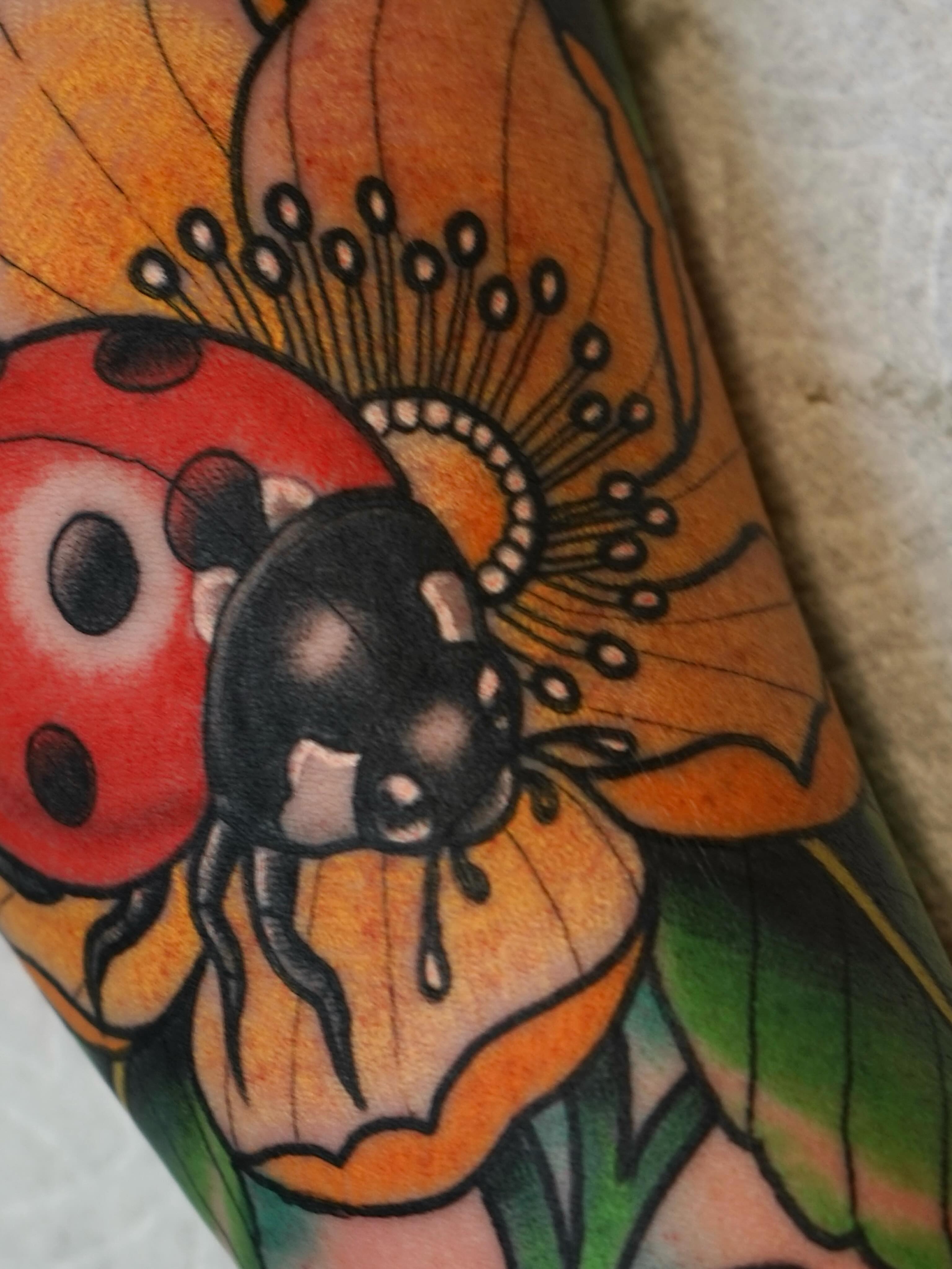Ladybug and flower American traditional tattoo on the forearm by Tyler Harrington