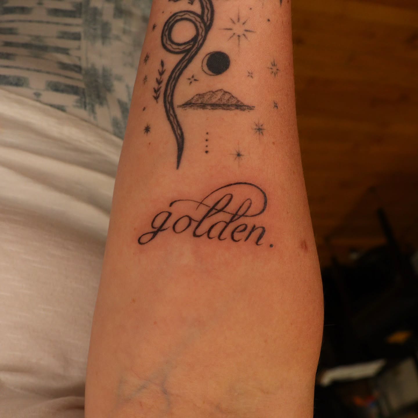 Golden lettering script tattoo on the forearm by Veronika Lipchak