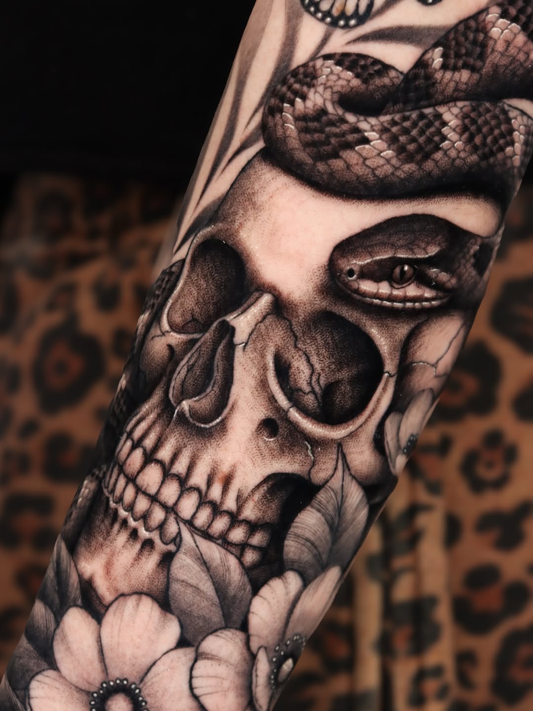 Skull with snake and flowers realism tattoo on the forearm by Jeff Reindel