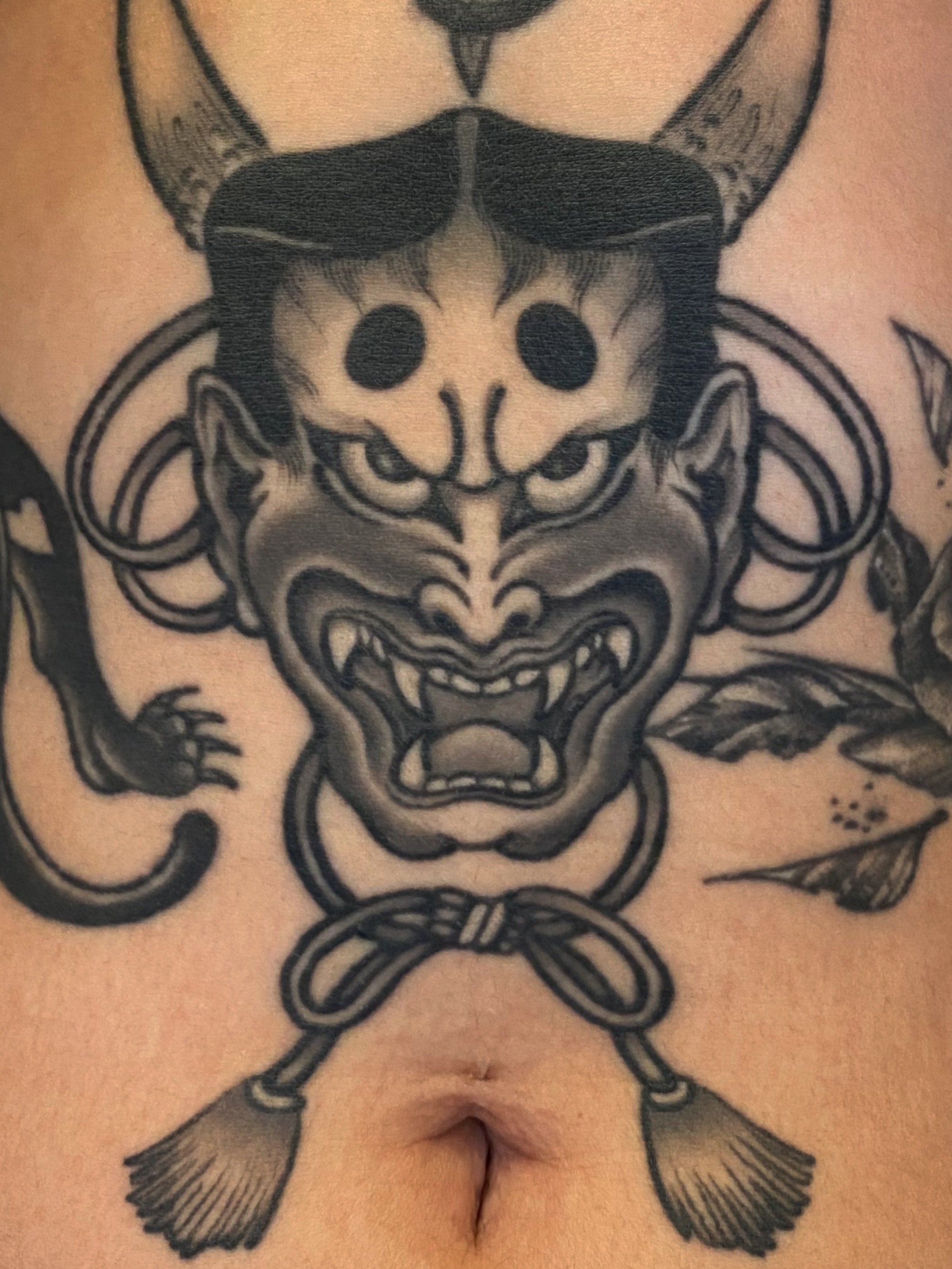 Demon mask black and grey tattoo on the torso by Mario Arcila