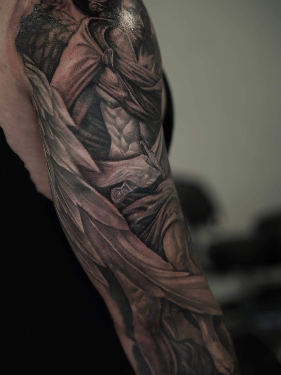 Figure with drapery realism tattoo on the upper arm by Nelson Tellez