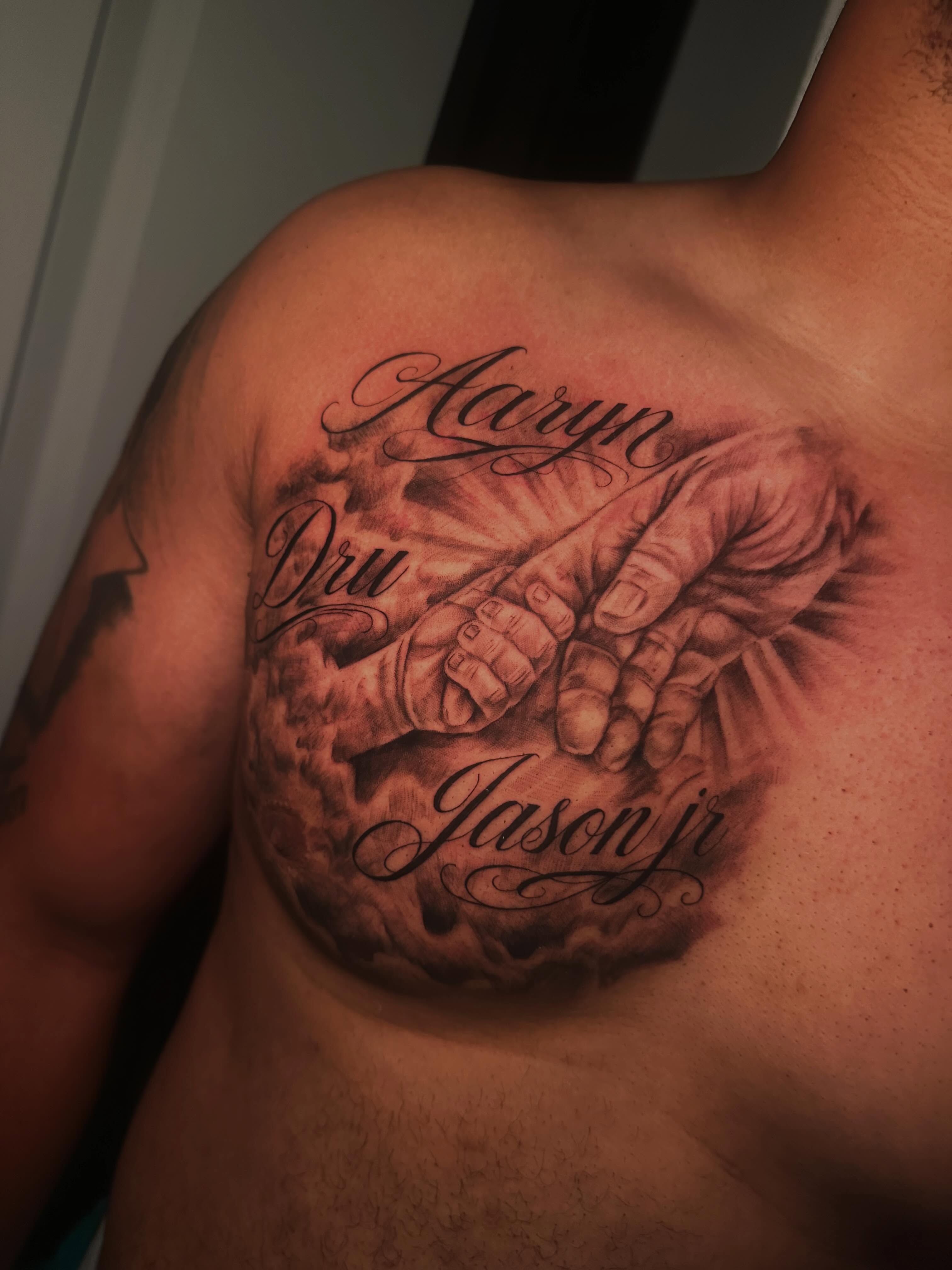 Hands and names realism tattoo on the chest by Tattoo Artist