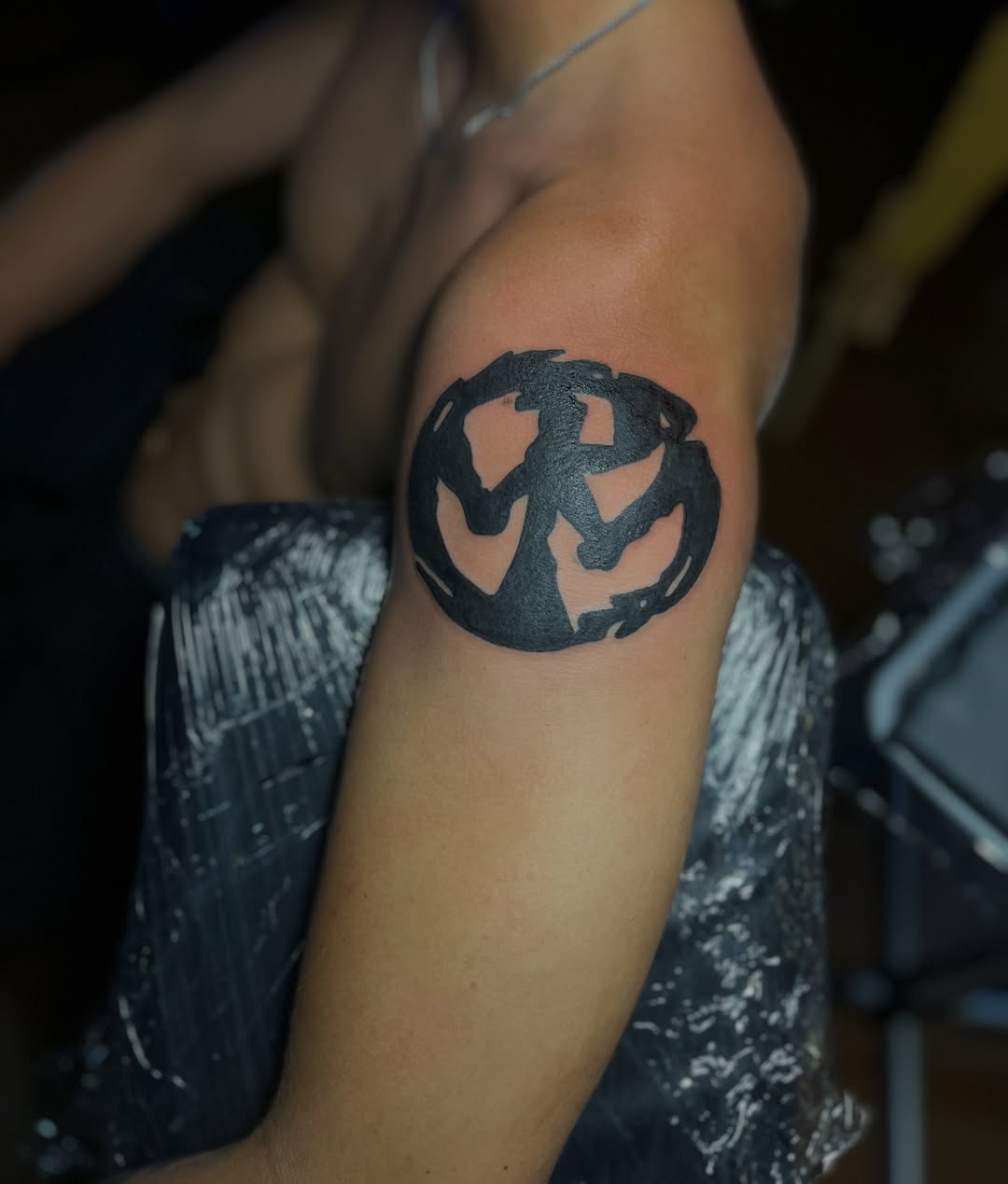 Circle with intertwined figures black and grey tattoo on the forearm by Eli Flores