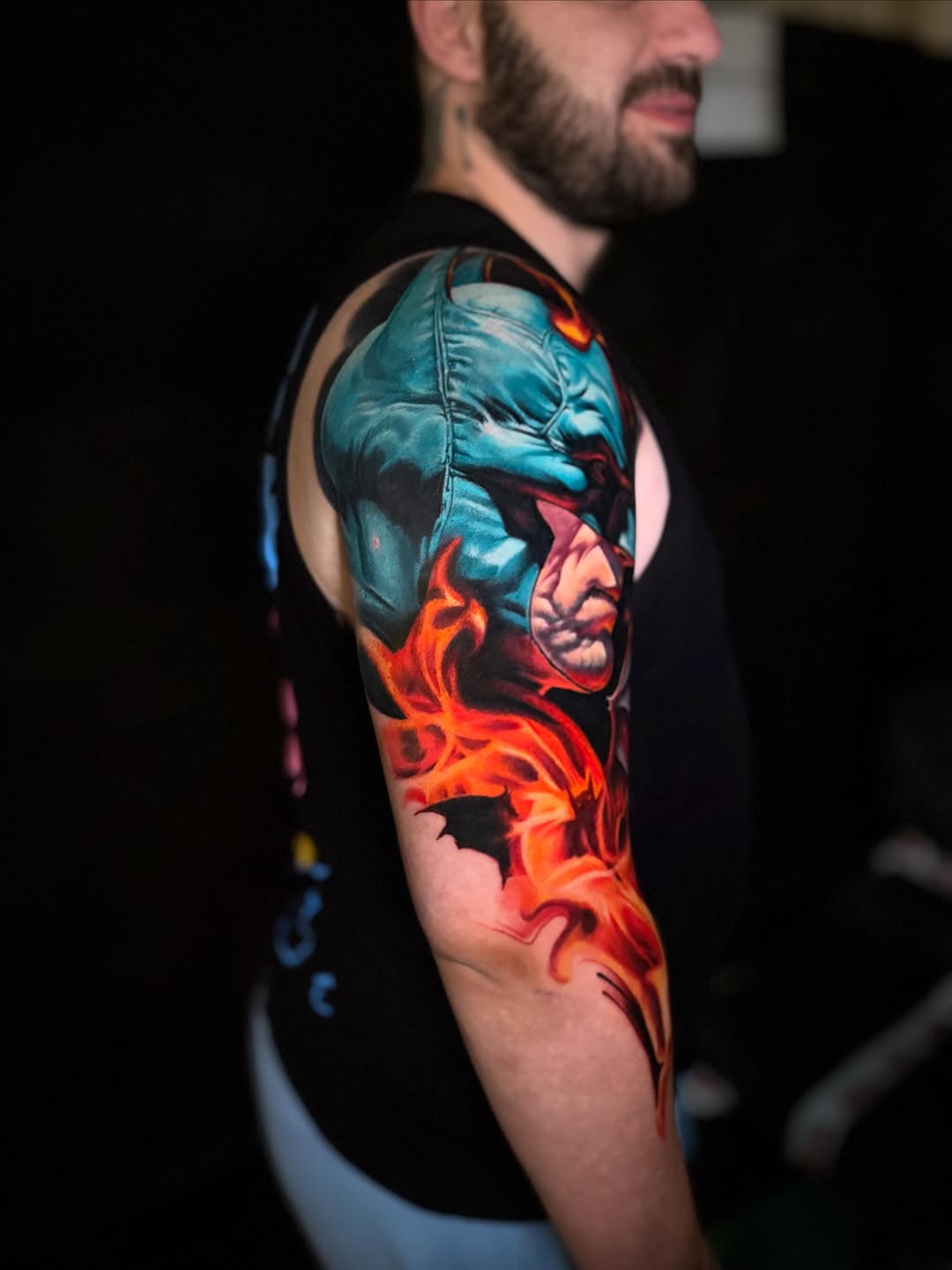 Batman with flames realism tattoo on the upper arm by Tony Ink