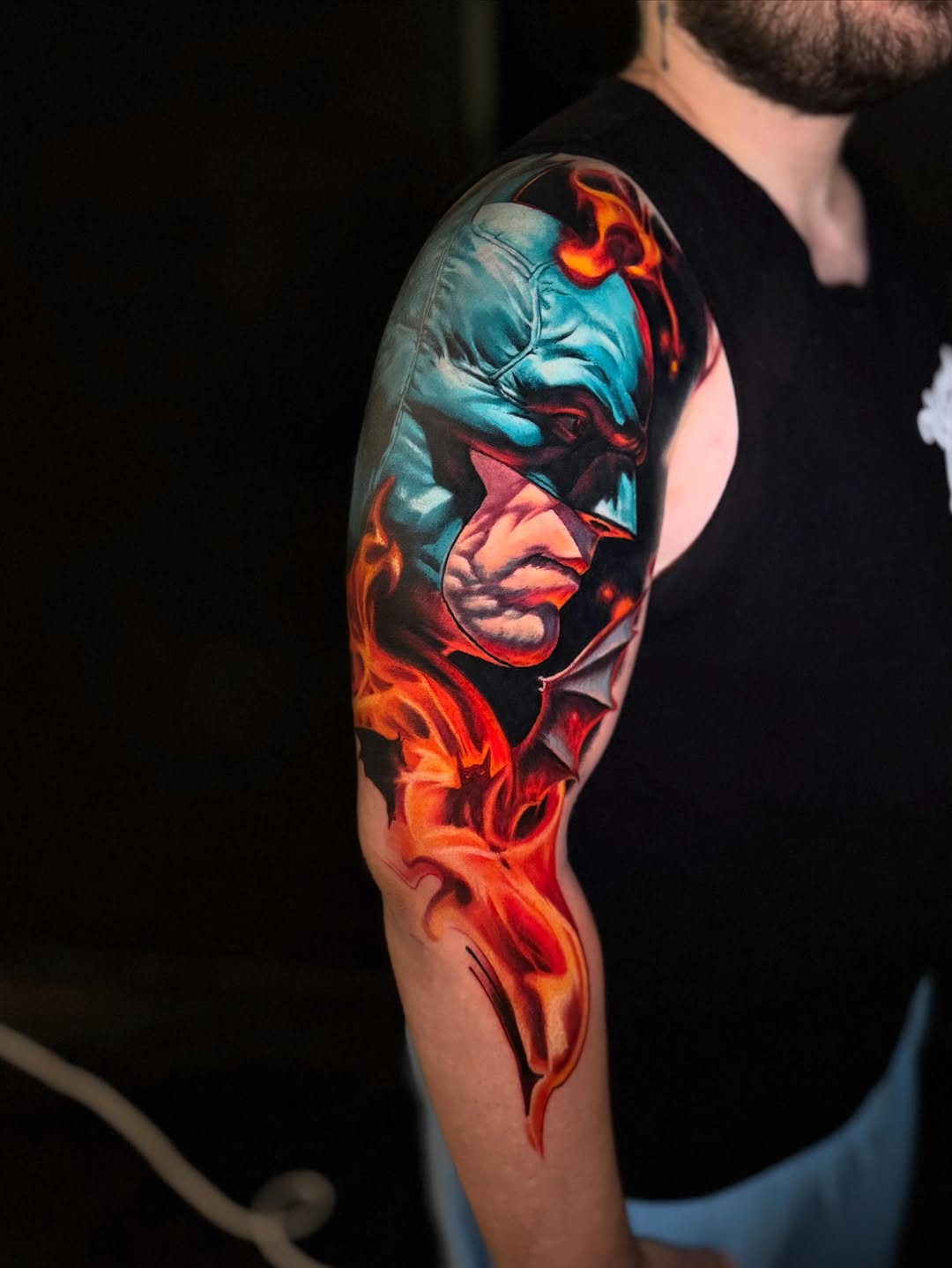 Batman with flames realism tattoo on the upper arm by Tony Ink